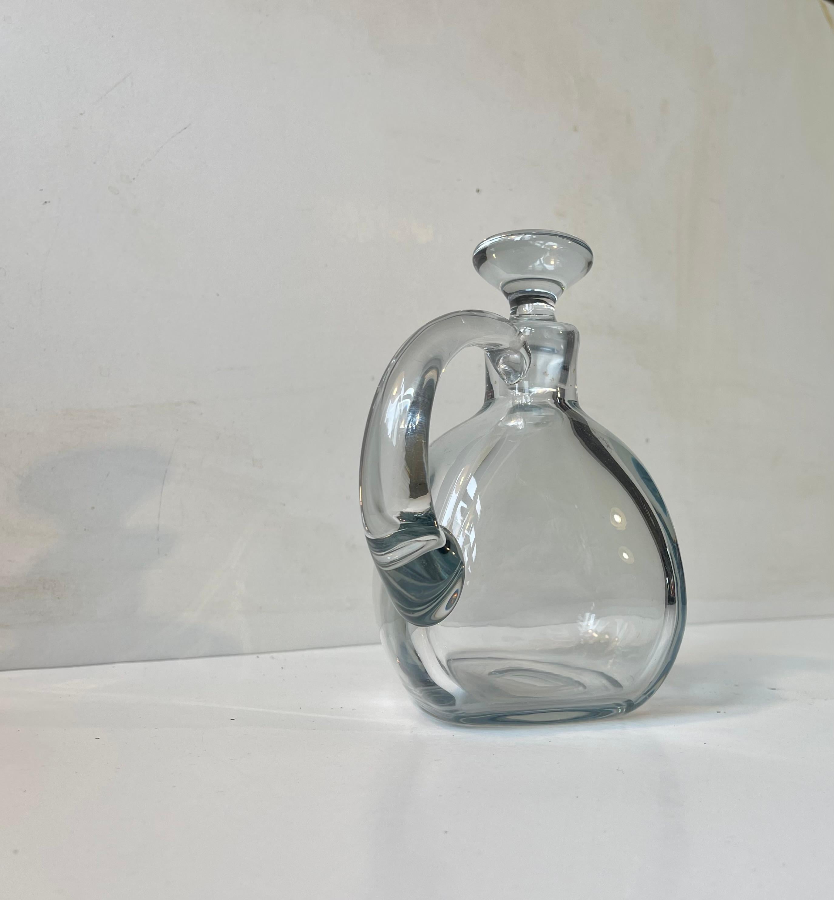 Free-form hand-blown decanter in blue-tinted glass. Made at Holmegaard in Denmark circa 1960-70. Probably designed by either Jacob E. Bang or Per Lütken. Un-catalogued however.
Very well-kept and clean. 

Measurements: H: 18 cm, W: 17 cm (with