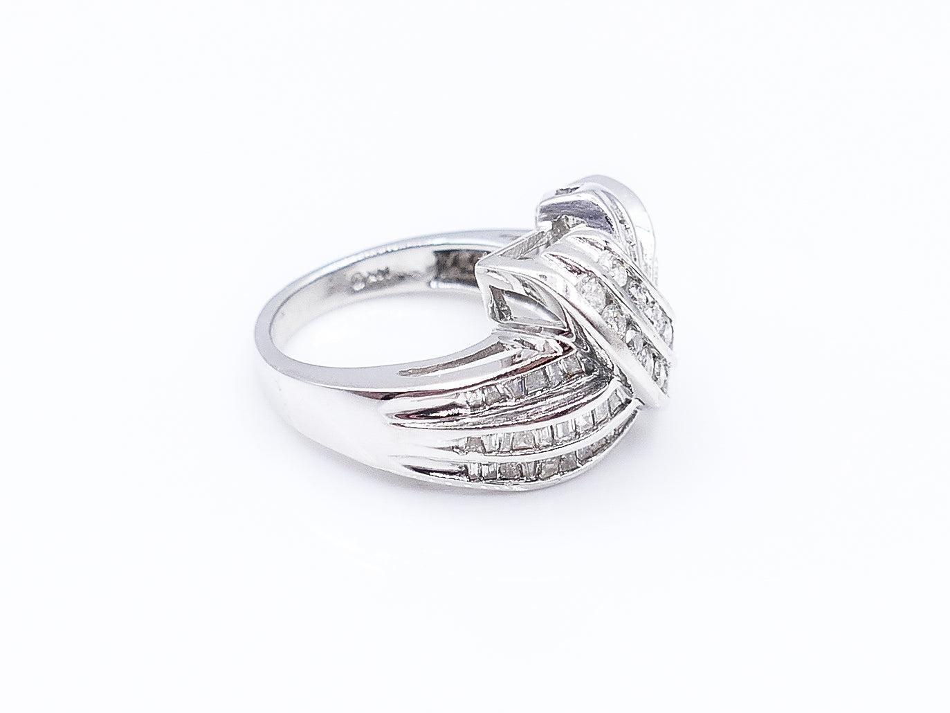 This beautiful asymmetrical ring is composed of 14 Karat White Gold and 59 Diamonds that weigh in at 2 Carats total. Two rows of round, channel-set Diamonds artfully overlap three rows of baguette Diamonds. 

7 g

Size 7