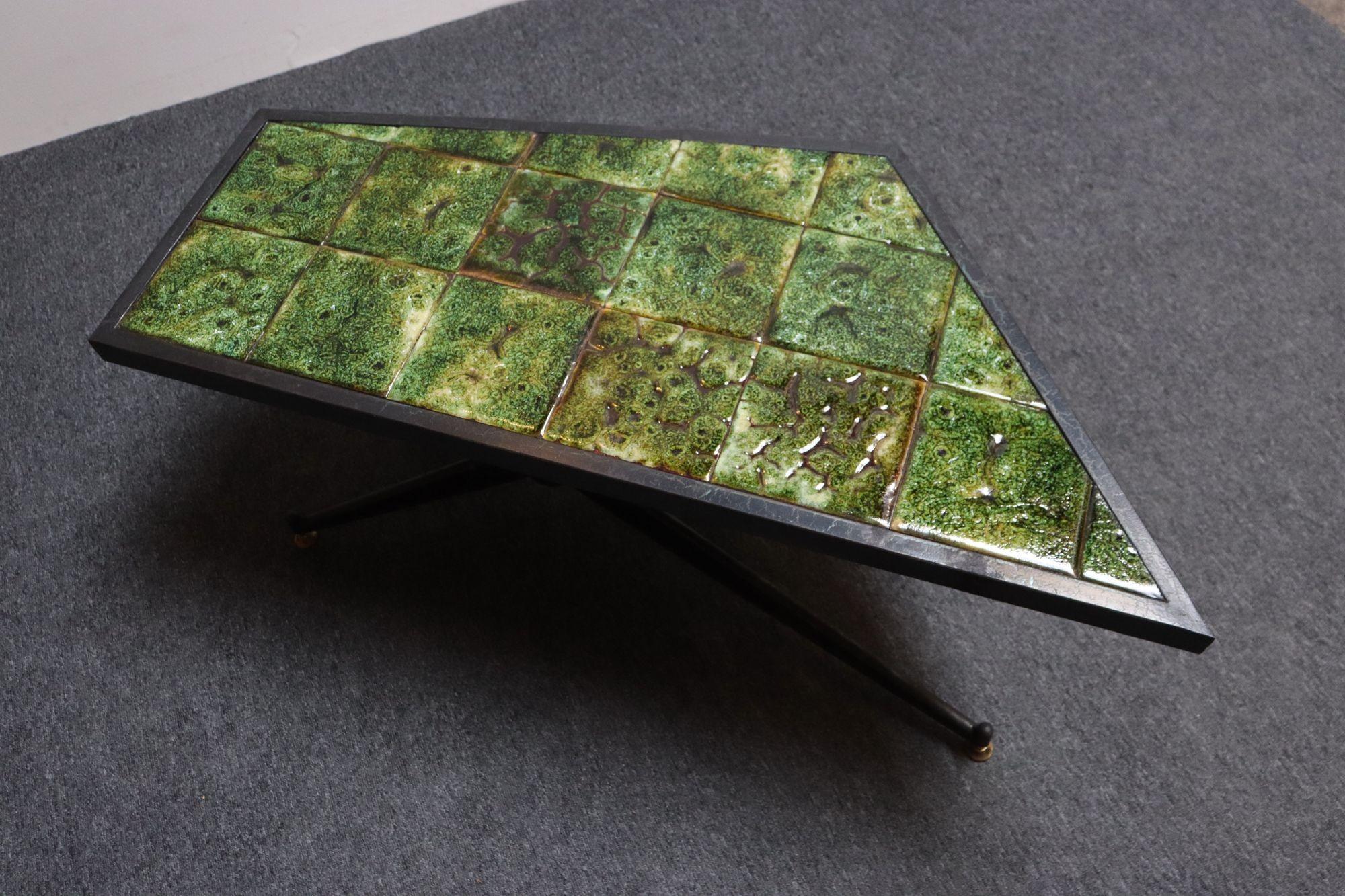 Tavolo da cocktail/caffè unico nel suo genere, composto da una struttura in ferro battuto con un piano asimmetrico/trapezoidale in piastrelle di ceramica verde incastonate sopra due superfici girevoli, il tutto sostenuto da gambe in ferro strombate