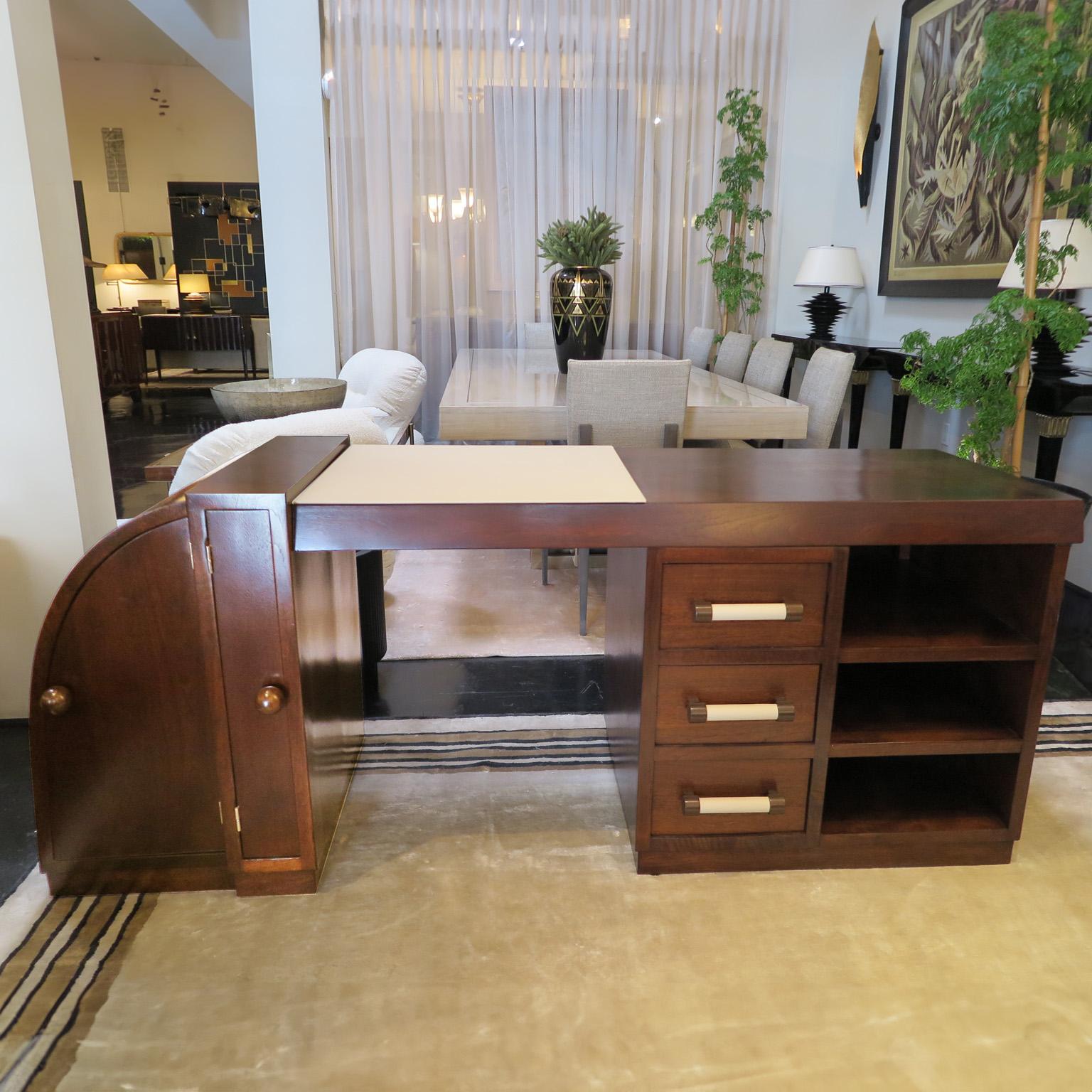Mid-Century desk in walnut with an open pore satin finish. The asymmetrical design offers a statement in any room. One side curves down with two compartment doors. The rectangular side features a long desk top with 3 drawers and 3 open compartments.