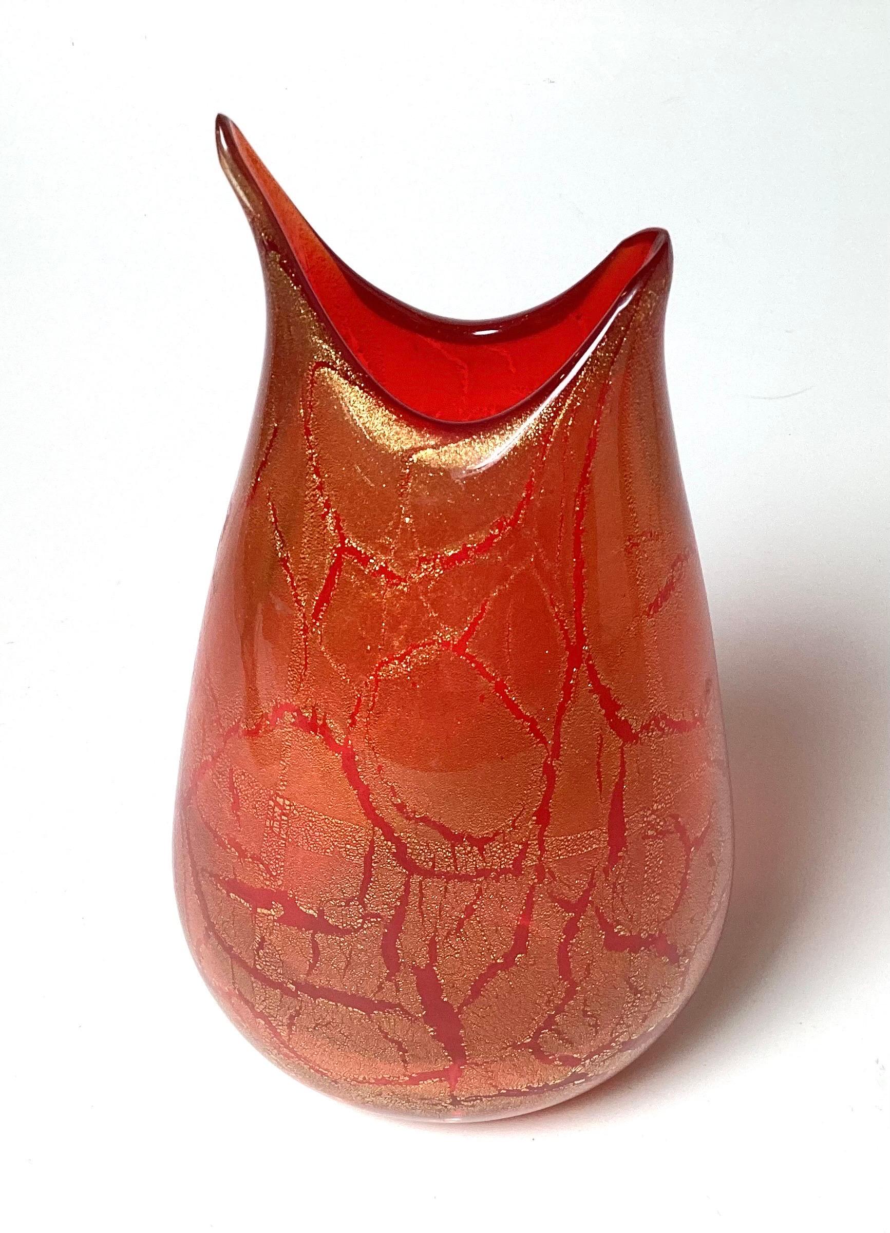 A 13 inch tall Italian Murano hand blown glass vase with clear, orange and gold inclusions attributed to Luca Vidal 
Color dominates over shape in Luca Vidal’s works: the imaginative blend of murrine and filigrane prepared by the Master, following