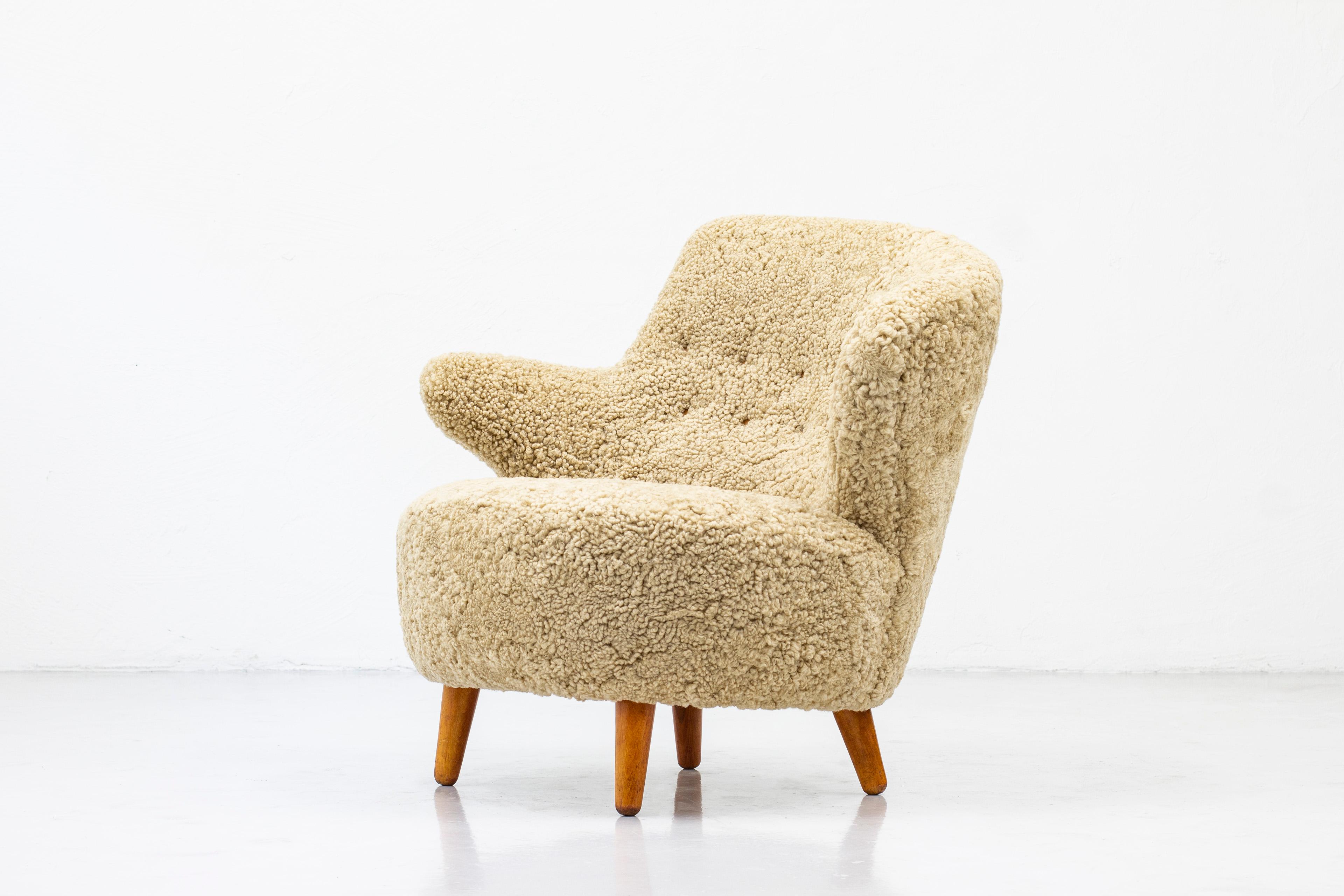 Very rare asymmetrical lounge chair produced by Norwegian company Vik & Blindheim. Made in Norway during the early 1950s. Legs made of beech wood and new upholstery in honey colored shearling fur, with cognac leather buttons. Signed with original