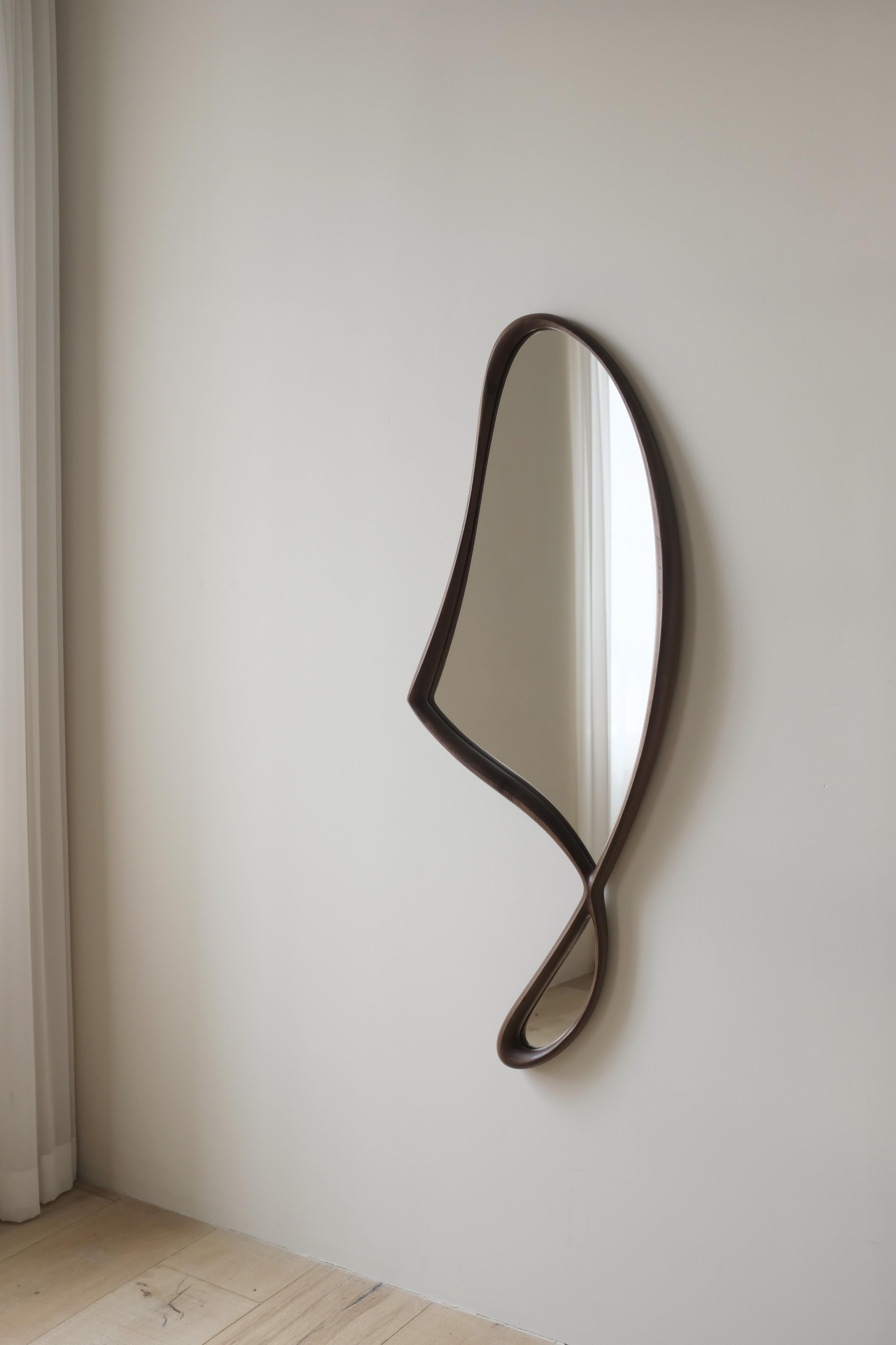 'Momentum Mirror II' by Soo Joo is a statement wooden wall mirror with a unique and timeless asymmetric form. This version of the mirror is in a cool Walnut Wood and a slightly smaller size than the bronze mirror. 

Momentum Mirror is a full-body