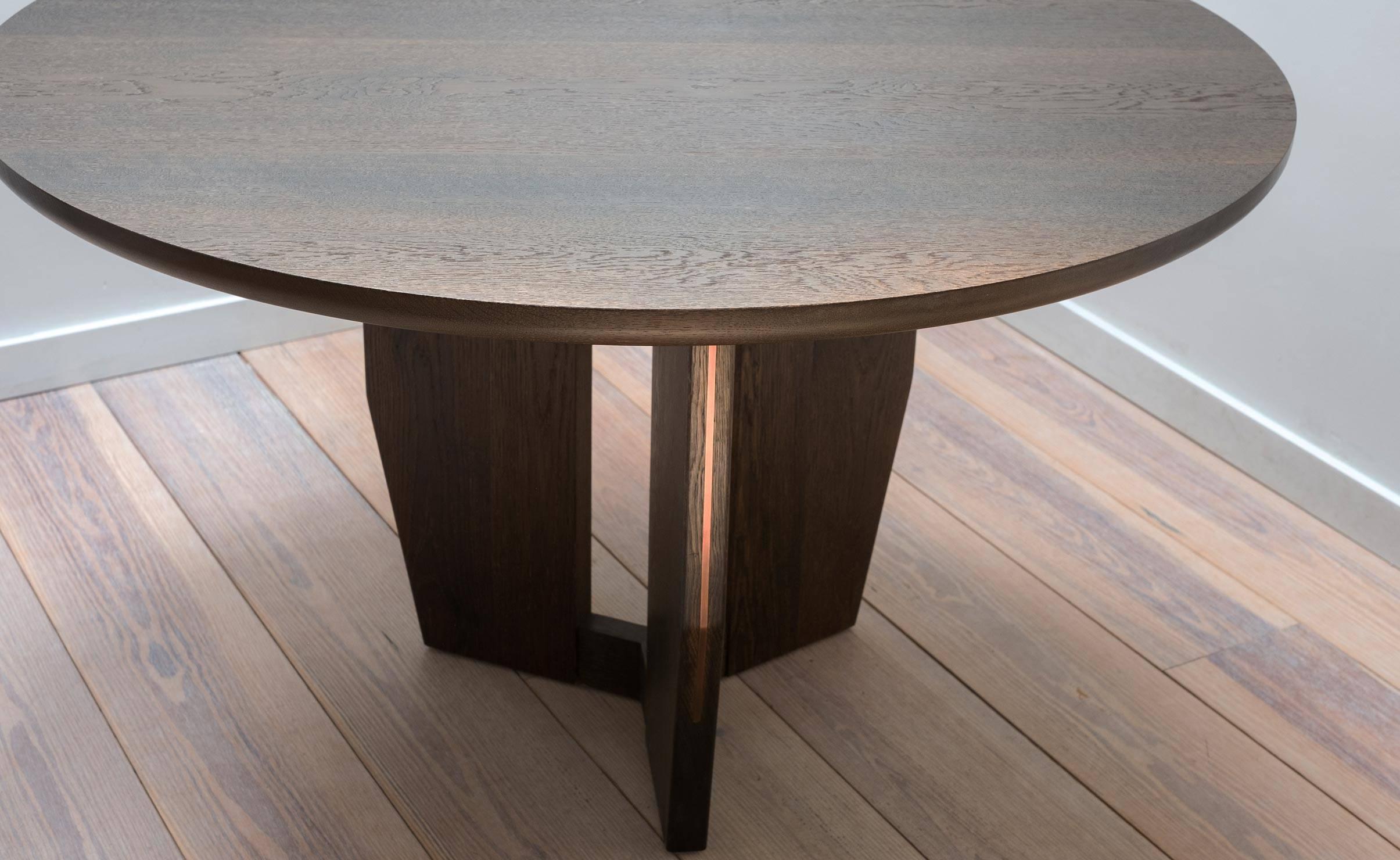 The Symmetrical Table, an elegant dining or center table, is made from hand-selected White Oak and features striking brass details. A trio of tapered wooden fins form a base of ample strength, but not mass. This piece is made by hand in Stillmade's