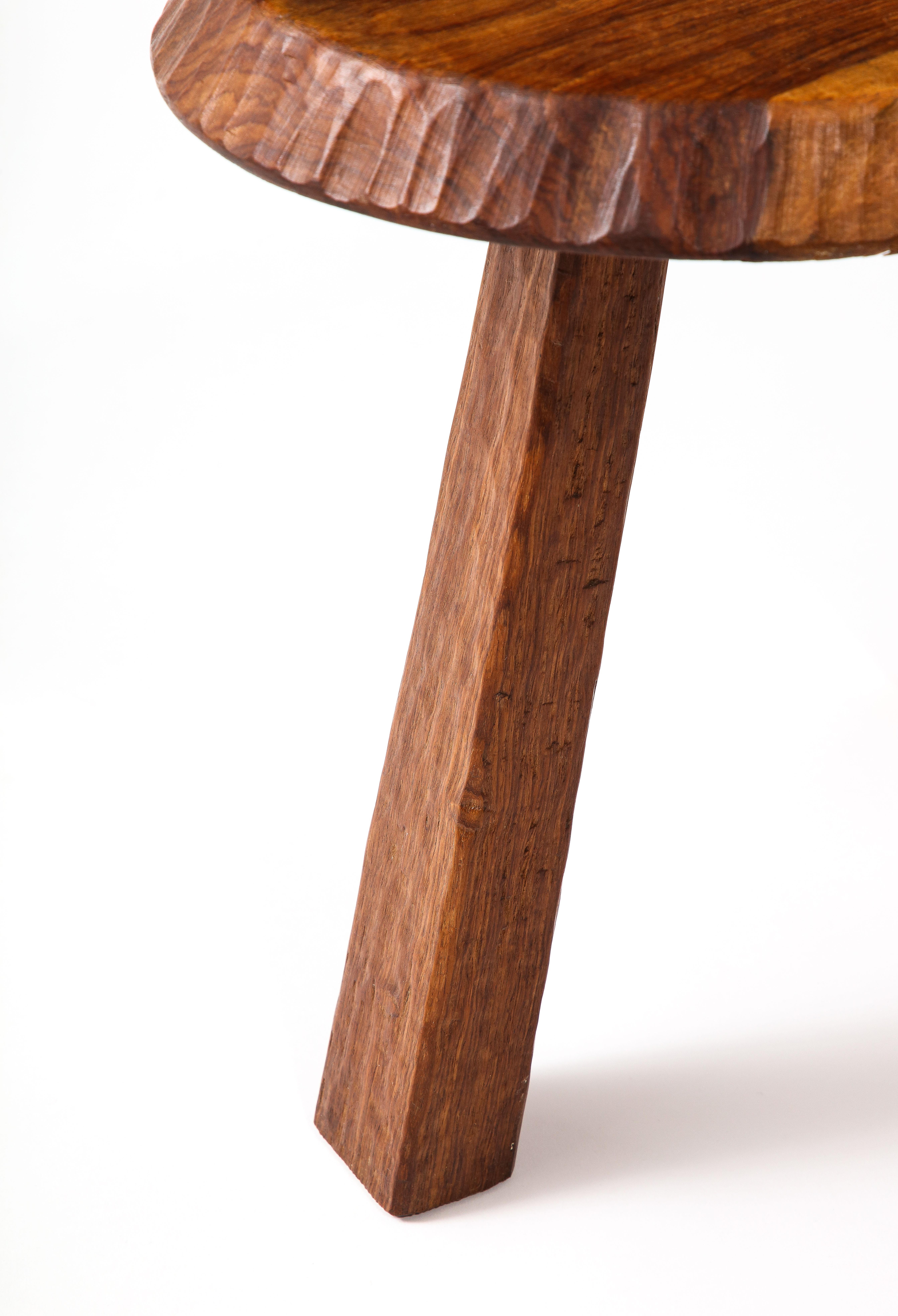 Solid carved walnut stool or occasional table with a gouged edge.

