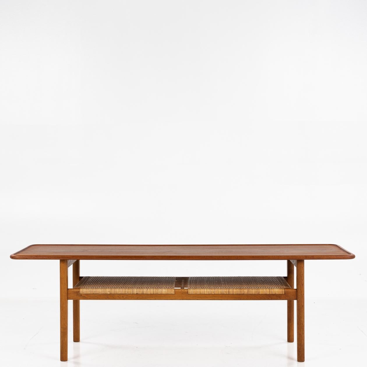 AT 10 - Coffee table in solid teak and oak frame with a shelf in cane.
Designed by Hans J. Wegner for cabinetmaker Andreas Tuck.