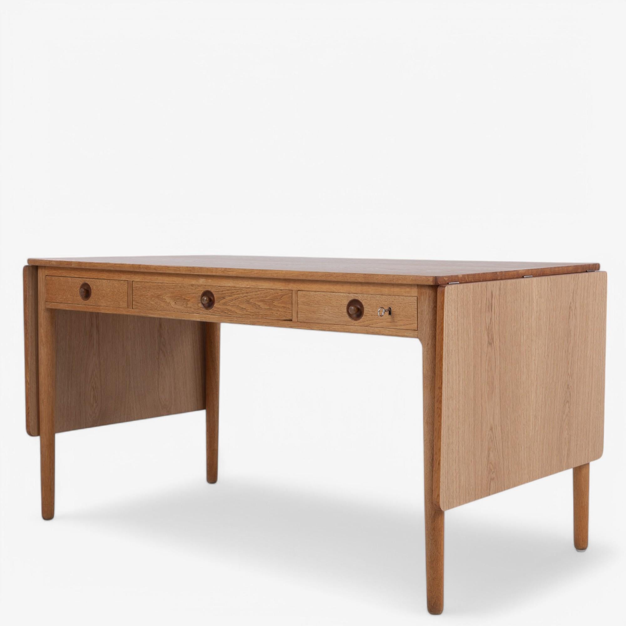 AT 305 - Scrivania in Oak con ribalte e tre cassetti. Le alette allungano il tavolo di 92 cm in più. Timbrata da Andreas Tuck. Progettato da Hans J. Wegner.