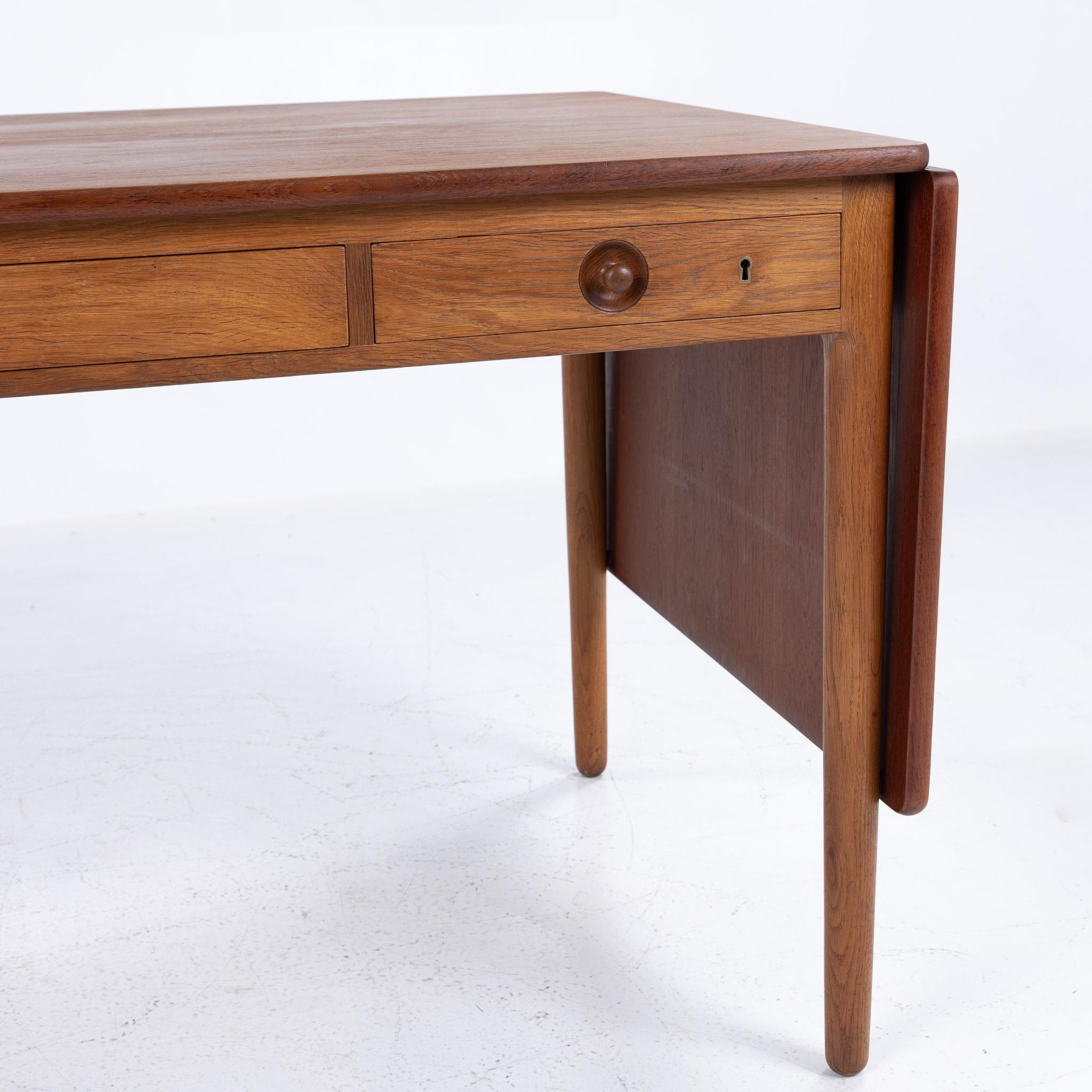 AT 305 - Scrivania in teak e Oak con ribalte e tre cassetti. Le alette aggiungono un totale di 92 cm in più.
Disegnato da Hans J. Wegner e realizzato da Andreas Tuck.