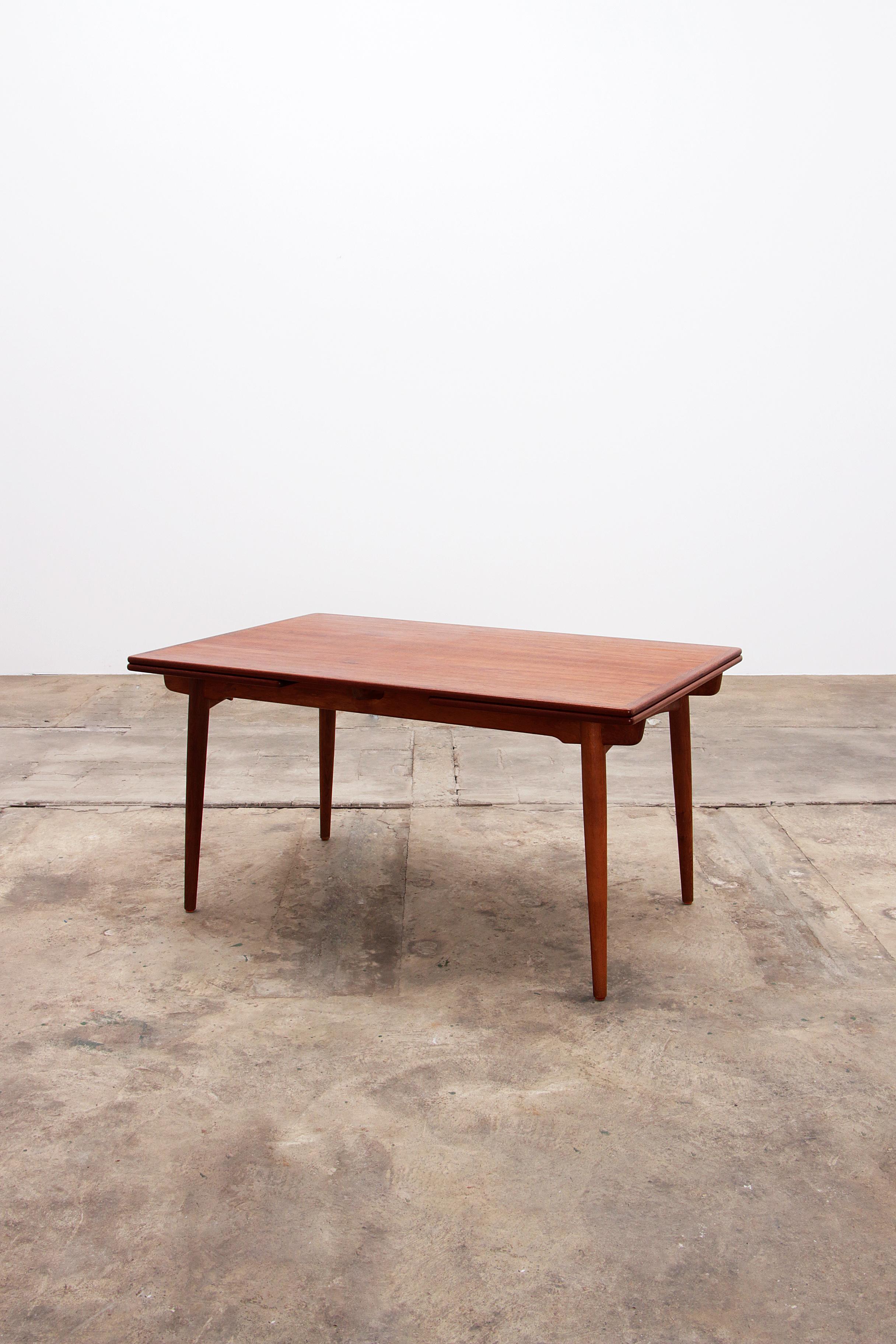 Hans J. Wegner Dining table from Andreas Tuck 
Extending dining table designed by Hans J. Wegner for Andreas Tuck in Denmark circa 1950. 
This iconic AT-312 model features a solid teak rectangular top and slanted tapered legs for a minimalist and