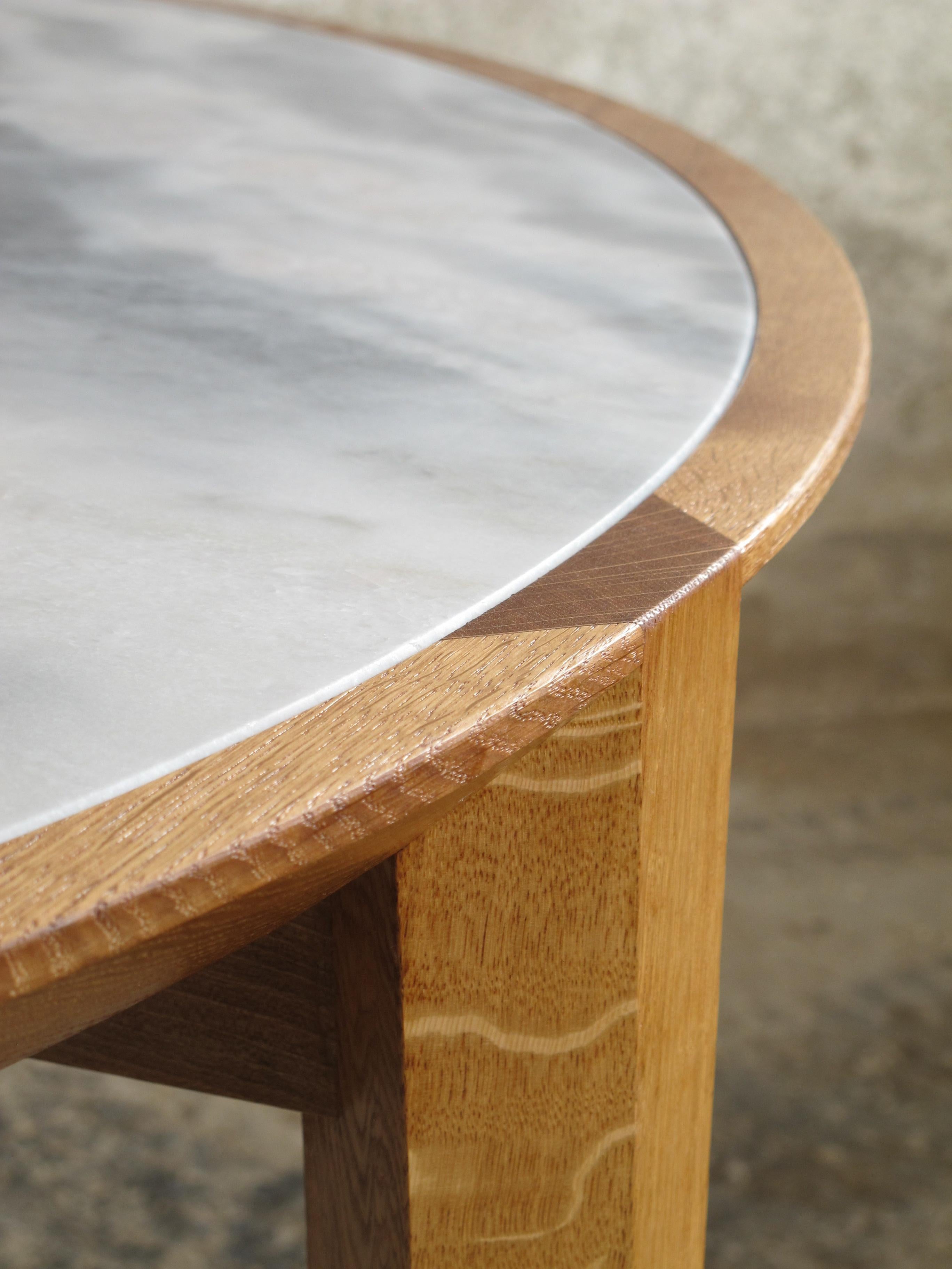 This carefully designed and handcrafted contemporary round wooden dinner table by Tomaz Viana holds a unique Estremoz marble top finely framed by a French oak stripe.

It´s elegant geometrical legs join the chamfered top revealing its grain in a