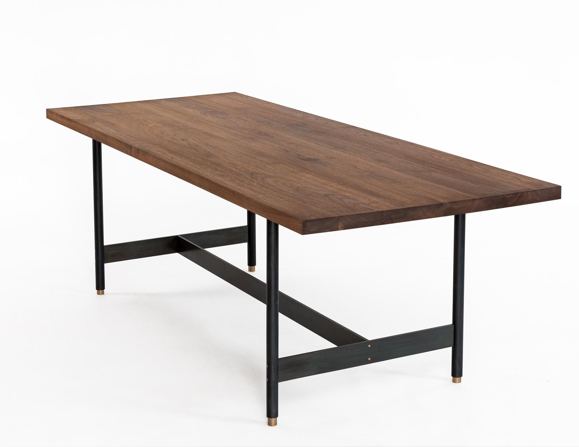 L'AT10 est une table de salle à manger en noyer massif fabriquée à la main, avec une base en acier noirci et des accents de bronze. Elle est parfaite pour la salle à manger, et ses lignes audacieuses et épurées s'adaptent à toutes les échelles,