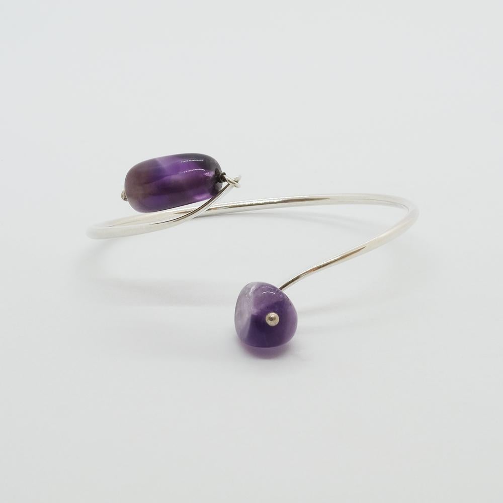This sterling silver cuff bracelet is adorned with two beautiful amethysts that look like bluebells. The cuff bracelet gently drops down the wrist but can, because it is somewhat stretchy, just as easily be worn upwards on the arm.

This cuff