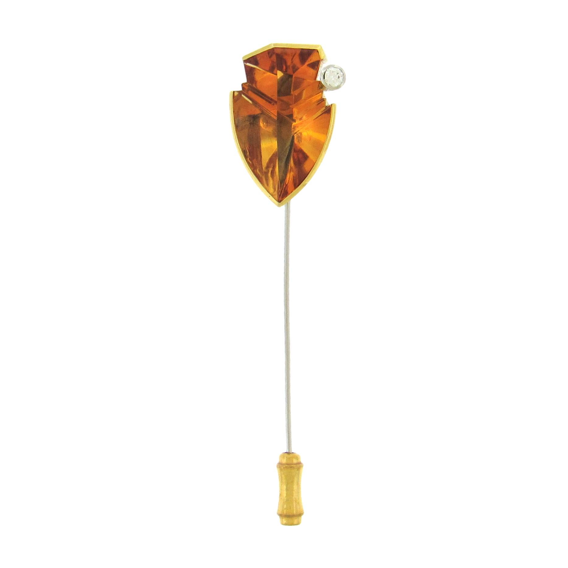 Tom Munsteiner arrowhead gem citrine stickpin, 13.45 cts, is a rich golden orange color highlighted by the sculptural undercutting of the gem. Set in 18K gold, diamond accent, steel pin. The mounted citrine measures 3/4″ x 1″ x 3/8″, the overall