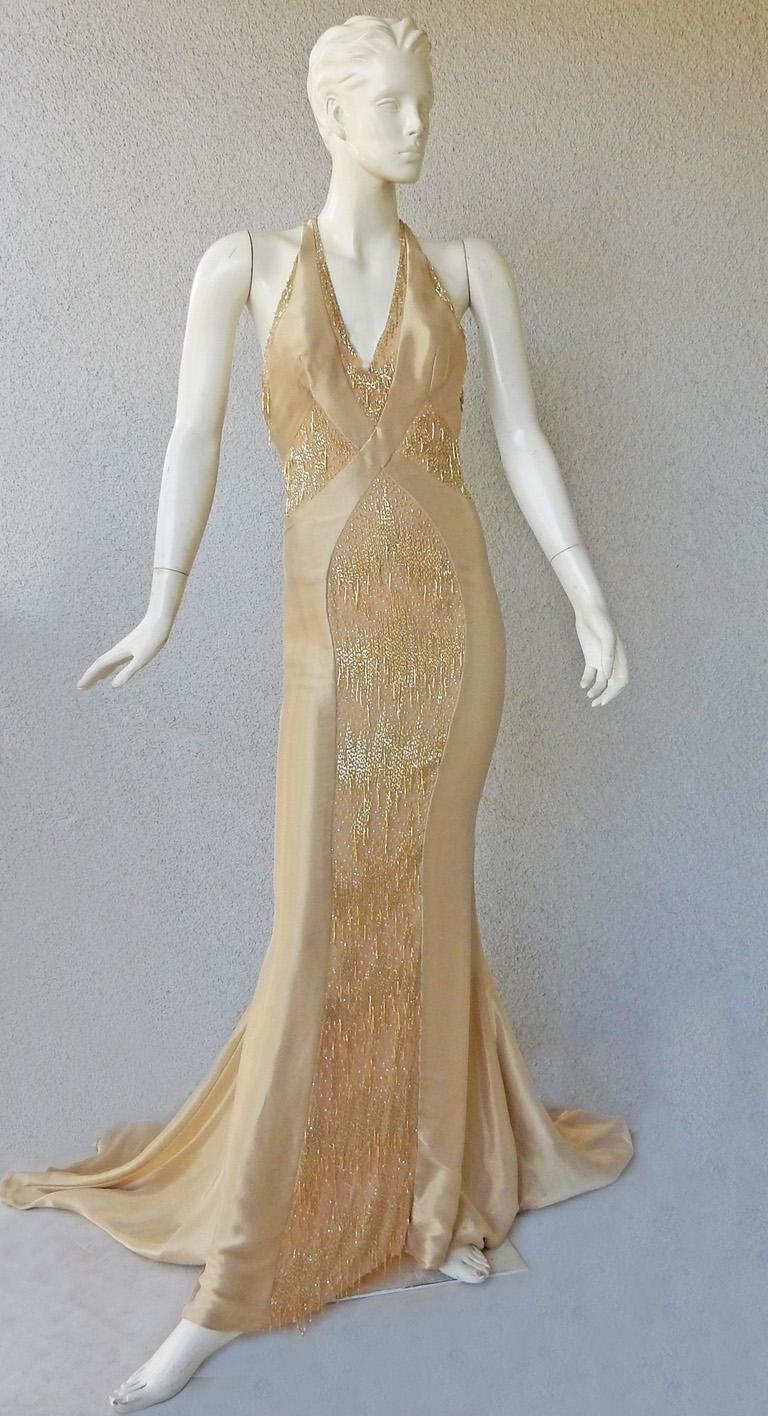 Atelier Versace custom-made beaded gown fashioned of golden champagne gossamer silk.  Gown features halter sweetheart neckline, corset interior boned bodice,  open T-back; fully lined and back zipper closure.  Further enhanced by panels of dripping
