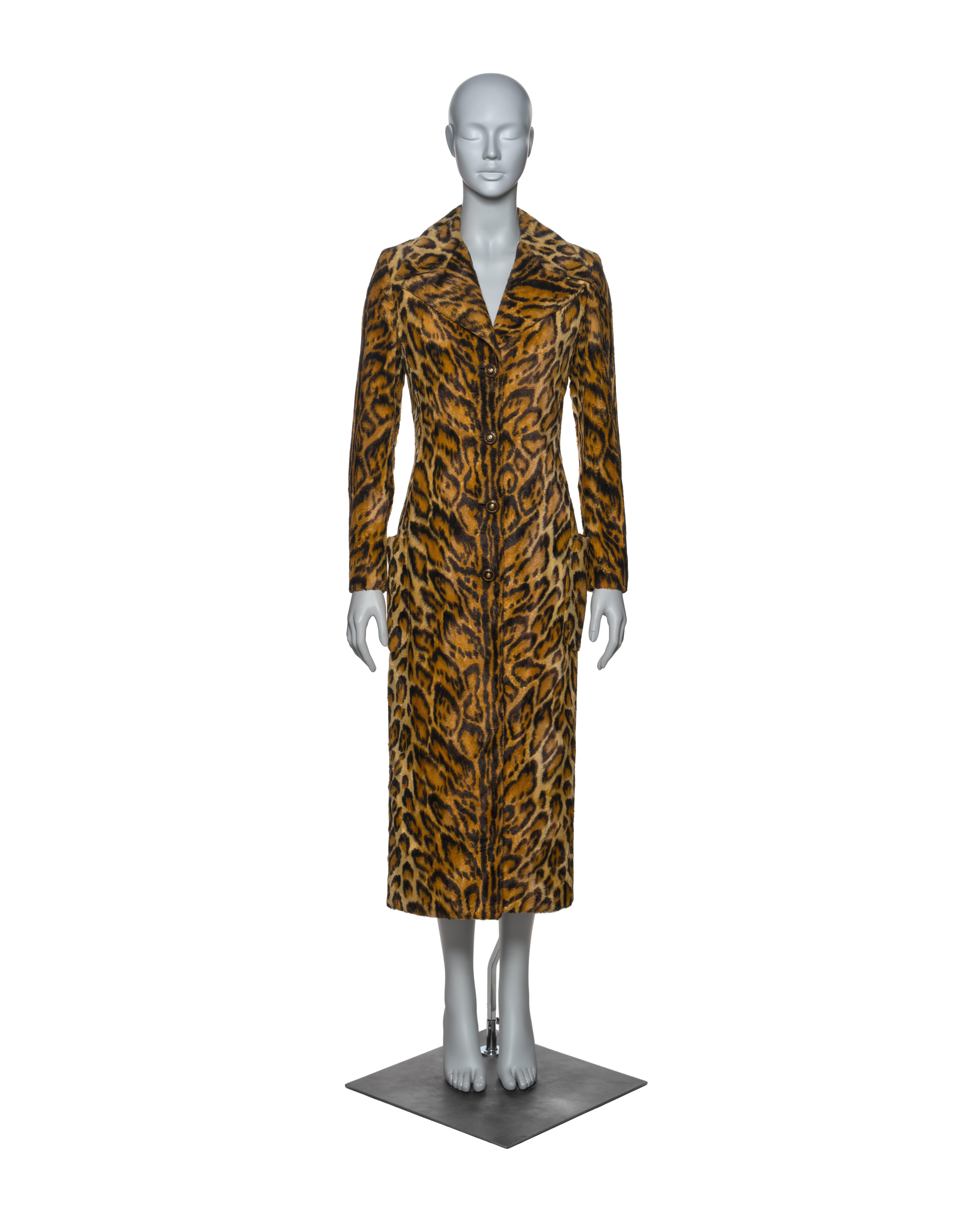 This Atelier Versace coat is a striking piece, crafted from leopard-print faux fur in rich golden brown and black tones. Tailored to accentuate the waist, it features a single-breasted silhouette with a mid-calf length. The coat is adorned with