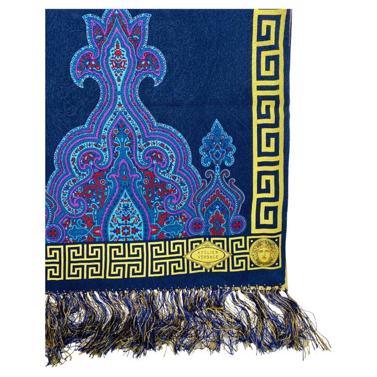 TheRealList presents: a stunning silk Atelier Versace scarf, designed by Gianni Versace. This beautiful scarf has a deep blue base with a baroque pattern, the back is a vibrant yellow. The edges of the scarf feature a yellow greek key and medusa