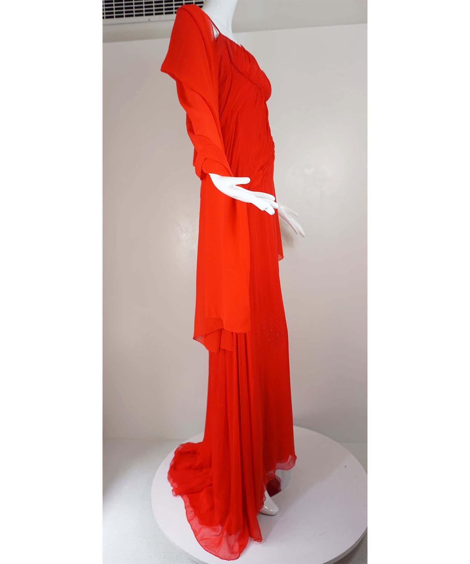 Das Kleid von Atelier Versace besteht aus rotem Seidenchiffon und einem passenden Perlenschal. Das maßgefertigte Kleid hat eine geraffte Brust und assymetrische Drapierungen mit Kristalldesigns und einen handgenähten Perlensaum über die drei