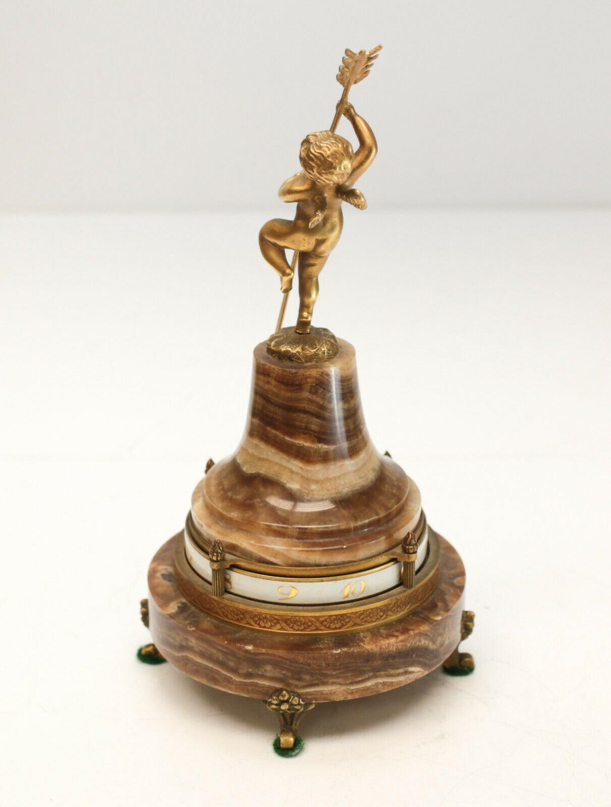 French Ateliers Juvenia gilt bronze onyx annular rotary clock #23656, circa 1925. The desk clocks are mounted but winged putti grasping long arrow with tip denoting hour and minute to circular partial gilt porcelain ring. Conical onyx body base