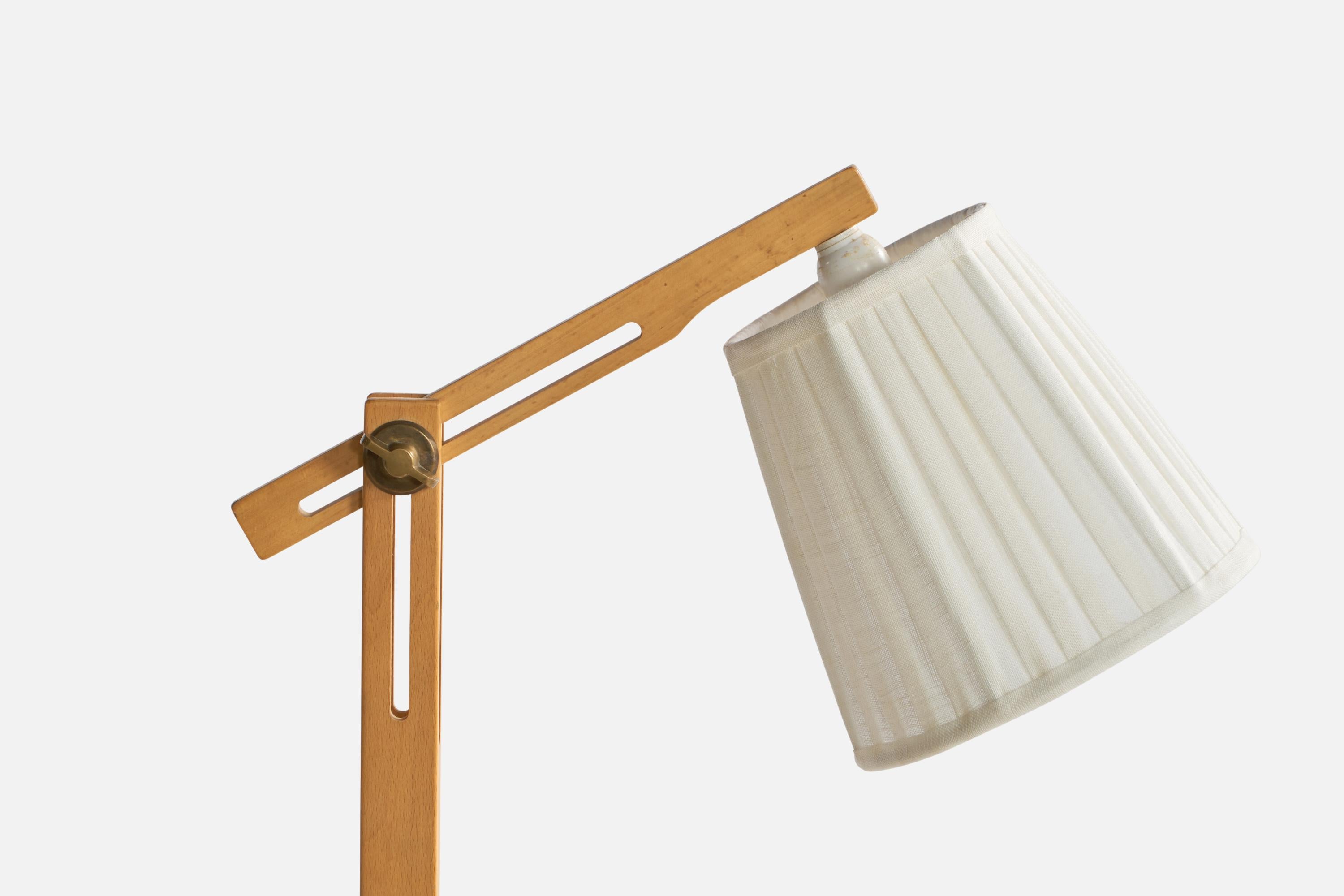 An adjustable oak, brass and white fabric floor lamp designed and produced by Ateljé Lyktan, Sweden, c. 1970s.

Overall Dimensions (inches): 50.5” H x 8” W x 6” D. Stated dimensions include shade.
Dimensions vary based on a position of light.
Bulb