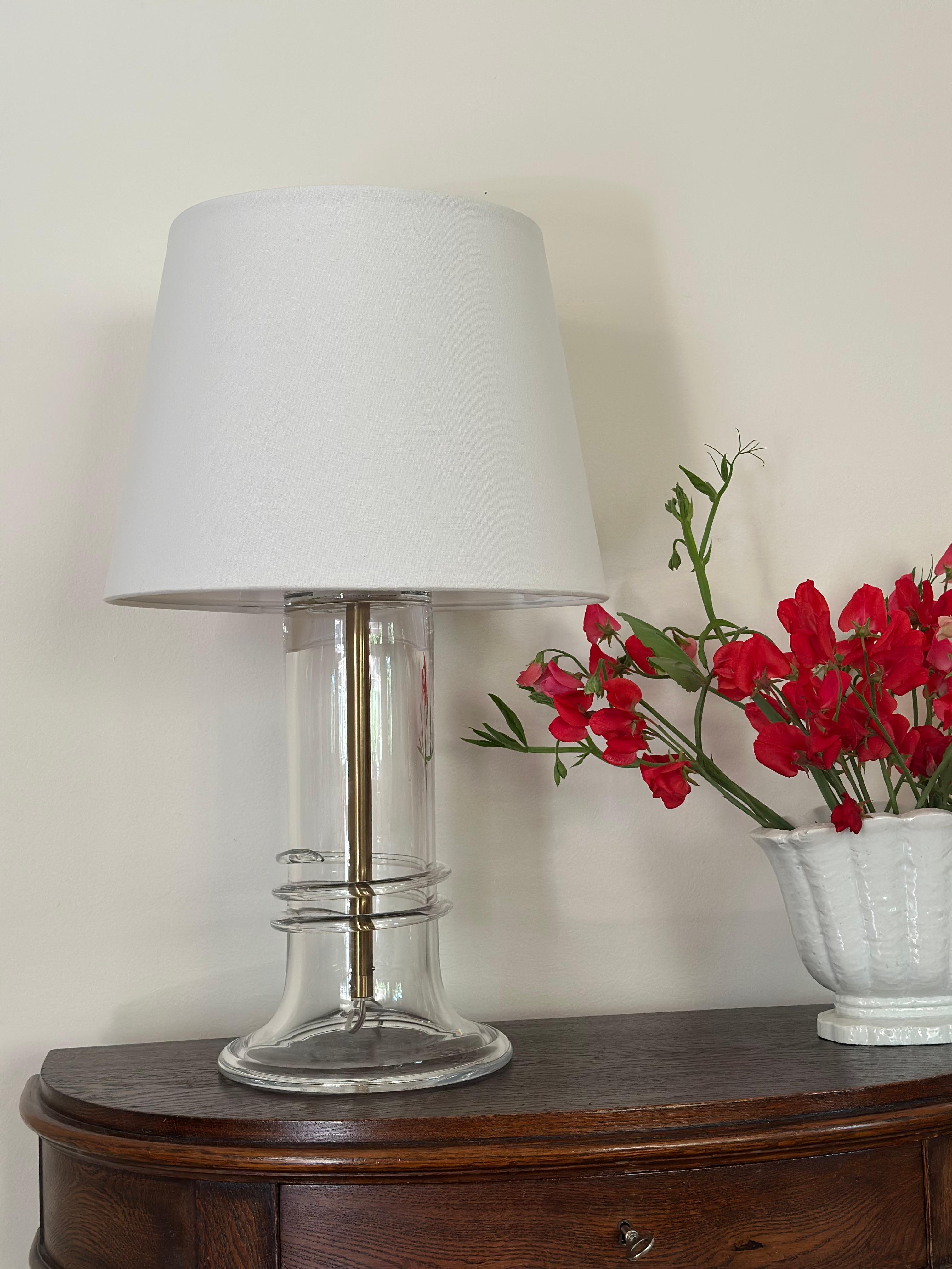 Atelje Lyktan Glass Table Lamp with brass stem & body in Clear Glass. Produced and manufactured in Sweden during the 1980s.

Design by Hanne Dreutler for Studio Åhus/Ateljé Lyktan.

The white lamp shades is included.

Great vintage condition with
