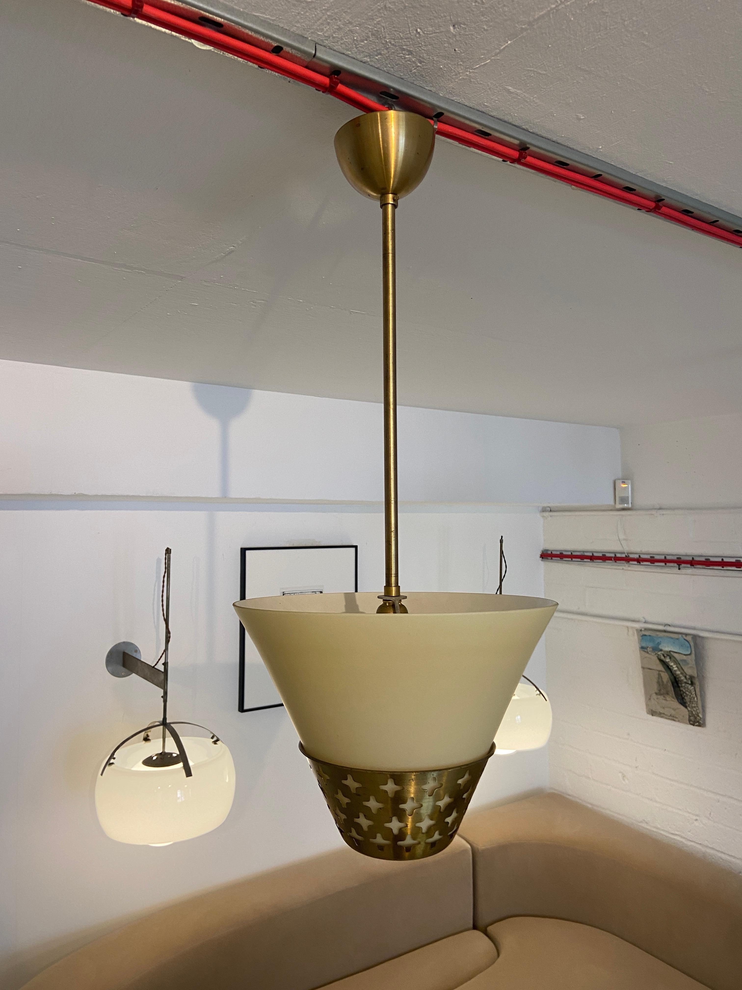 Questa raffinata lampada a sospensione è una miscela armoniosa di estetica moderna e artigianato impeccabile. Caratterizzato da un design elegante e ornamentale realizzato in ottone finemente traforato, emana un'aria di eleganza e raffinatezza che