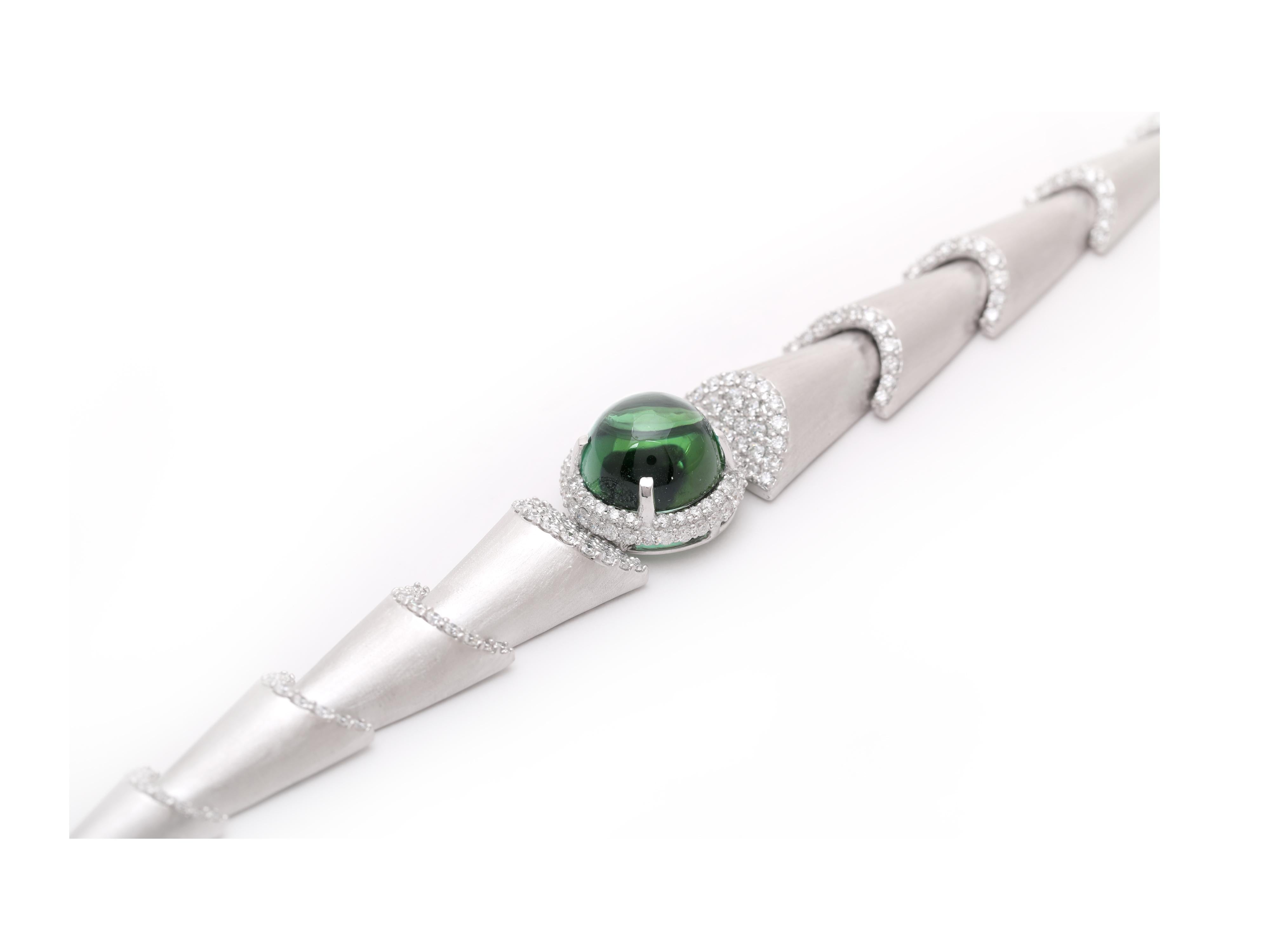 An stunning 6.87 carat green tourmaline cabochon lies at the heart of this exquisitely crafted diamond bracelet in 18k white gold.

The tapering design and cascading elements combine to achieve the impression of movement, while the textured gold
