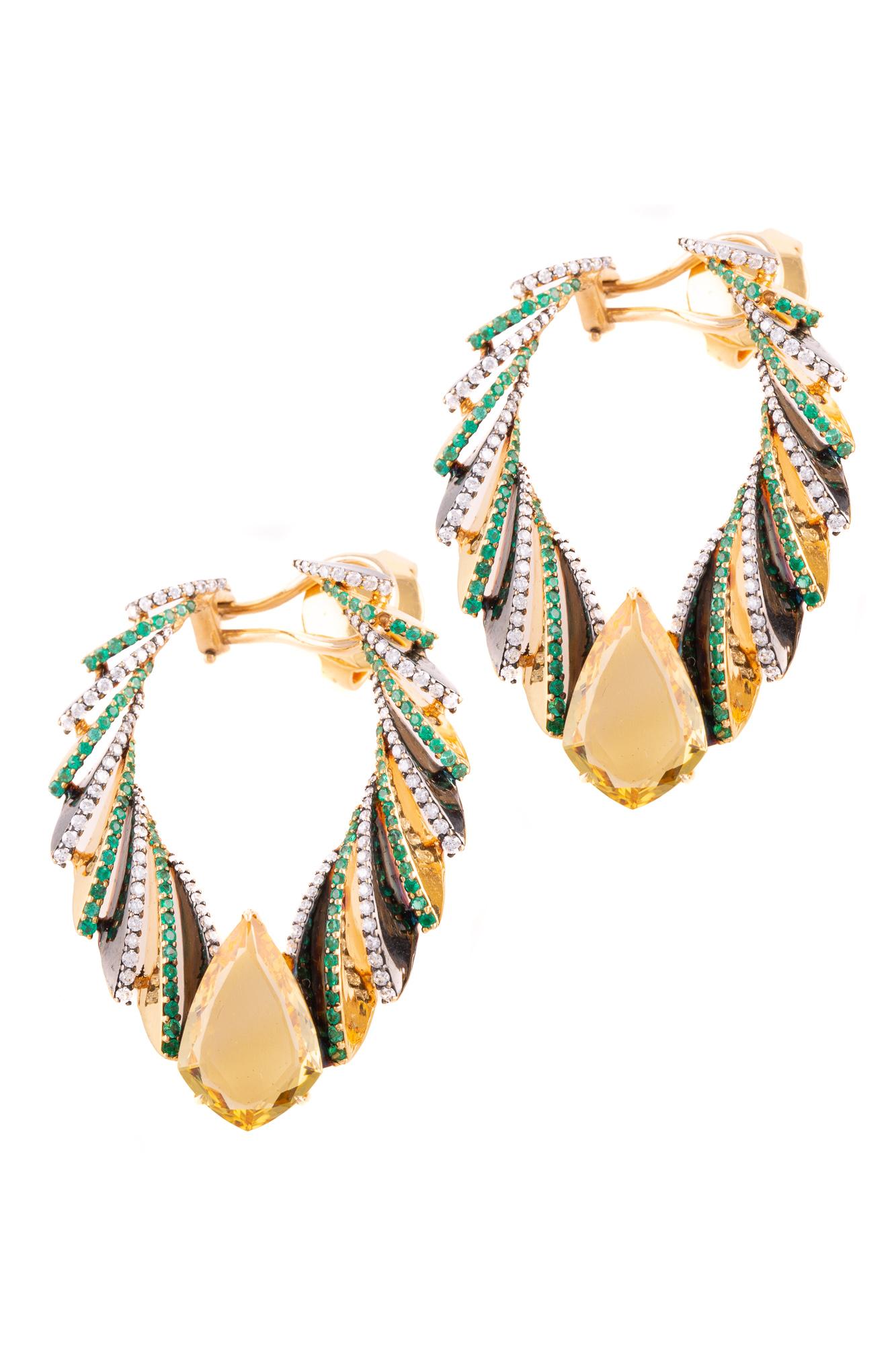 Two spectatular shield-cut pieces of yellow beryl take up center stage in these earrings in 18k yellow gold, flanked by brilliant-cut white diamonds and emeralds.

A dramatic black finish is applied in alternating sections, producing an effect