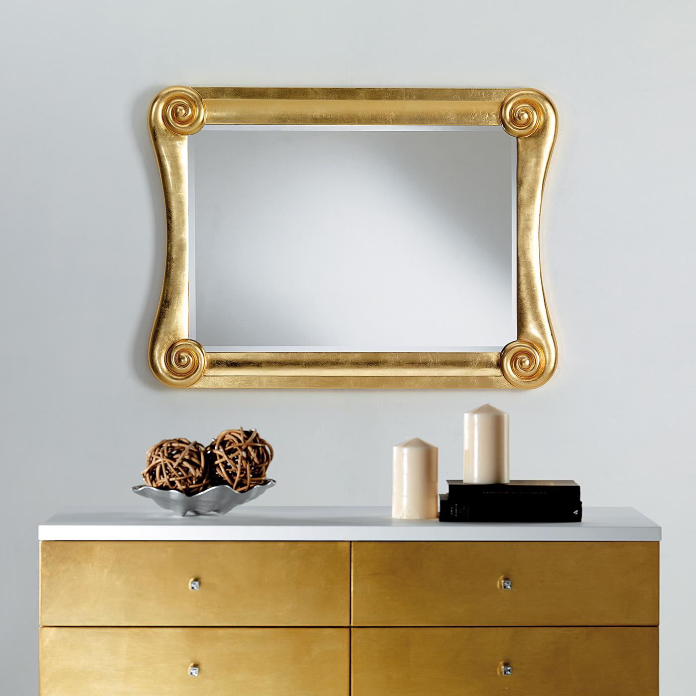 Boasting a fascinating silhouette enriched with neoclassic decorations, this rectangular wall mirror will be a precious addition to luxe decors. The wooden frame (14 cm large and 8 cm thick) is covered with gold leaf and showcases volutes in Ionic