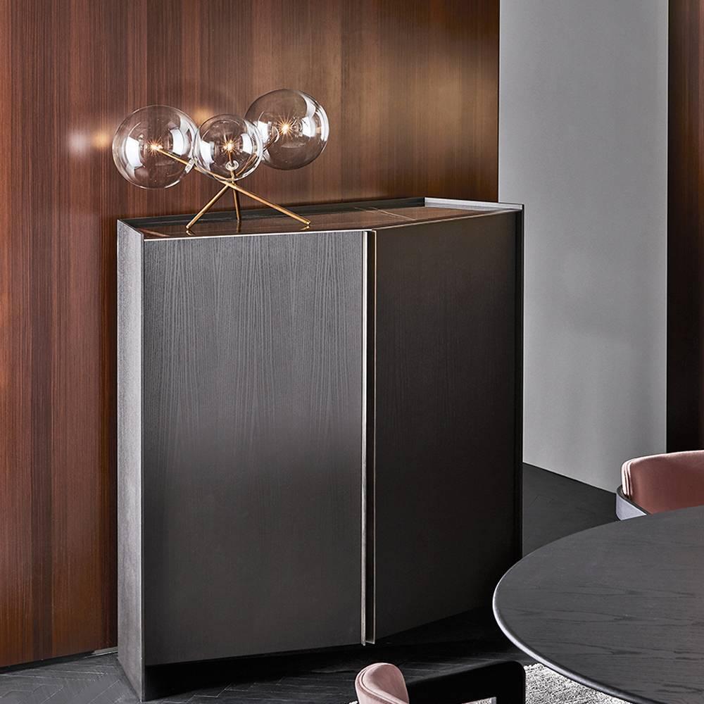 Sideboard in black open pore lacquered ash. Patinated bronze lacquered metal details.
Available with a grey stardust or Sahara Noir marble top.
Supplied with 10mm tempered extra light inside glass shelf. Push-pull drawers with suede bottom.