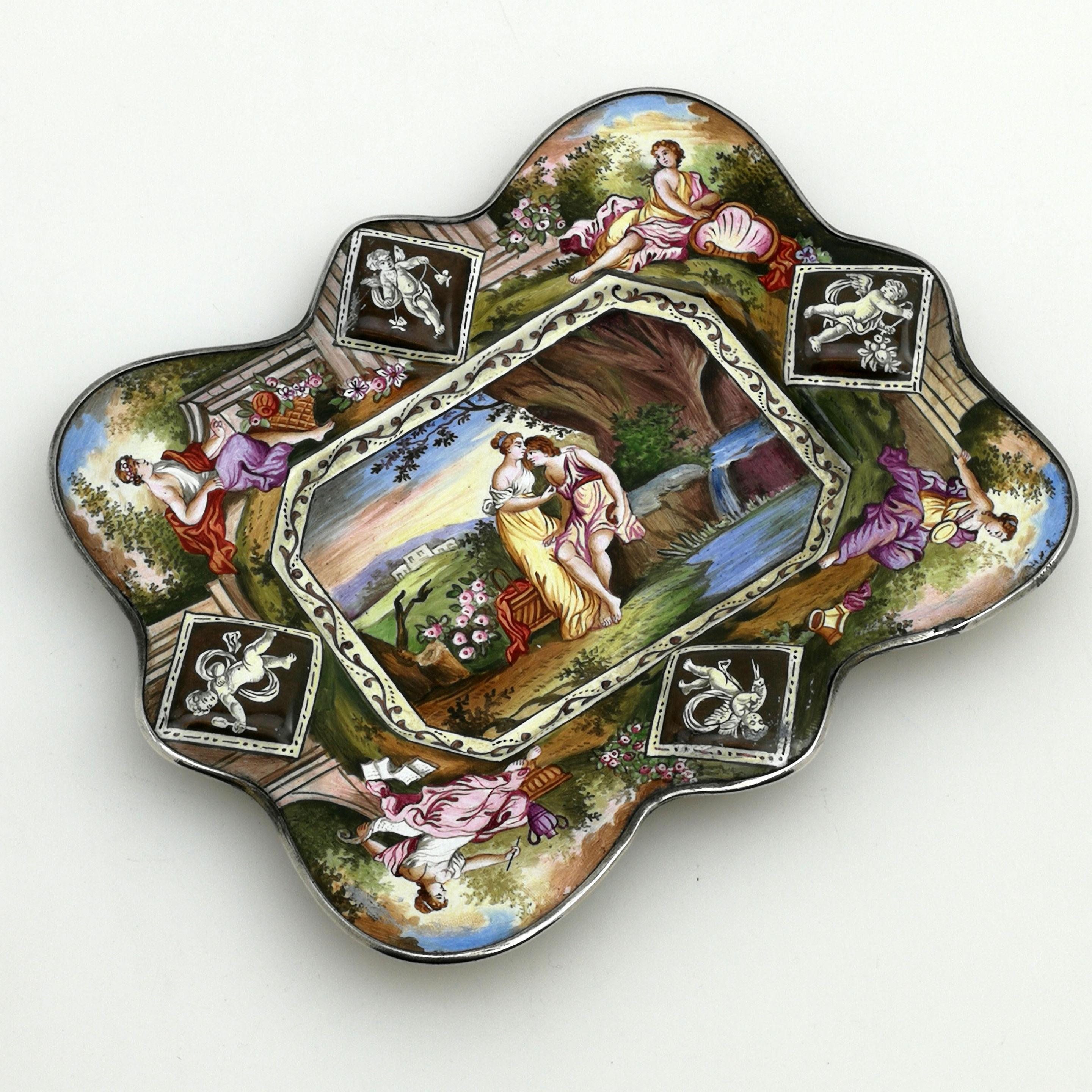 A pretty antique silver mounted Viennese enamel dish. This shaped rectangular dish features gorgeous enamel imaged across the entire top surface. The underside has a lovely monochrome scene surrounded by a subtle patterned border. The Interior