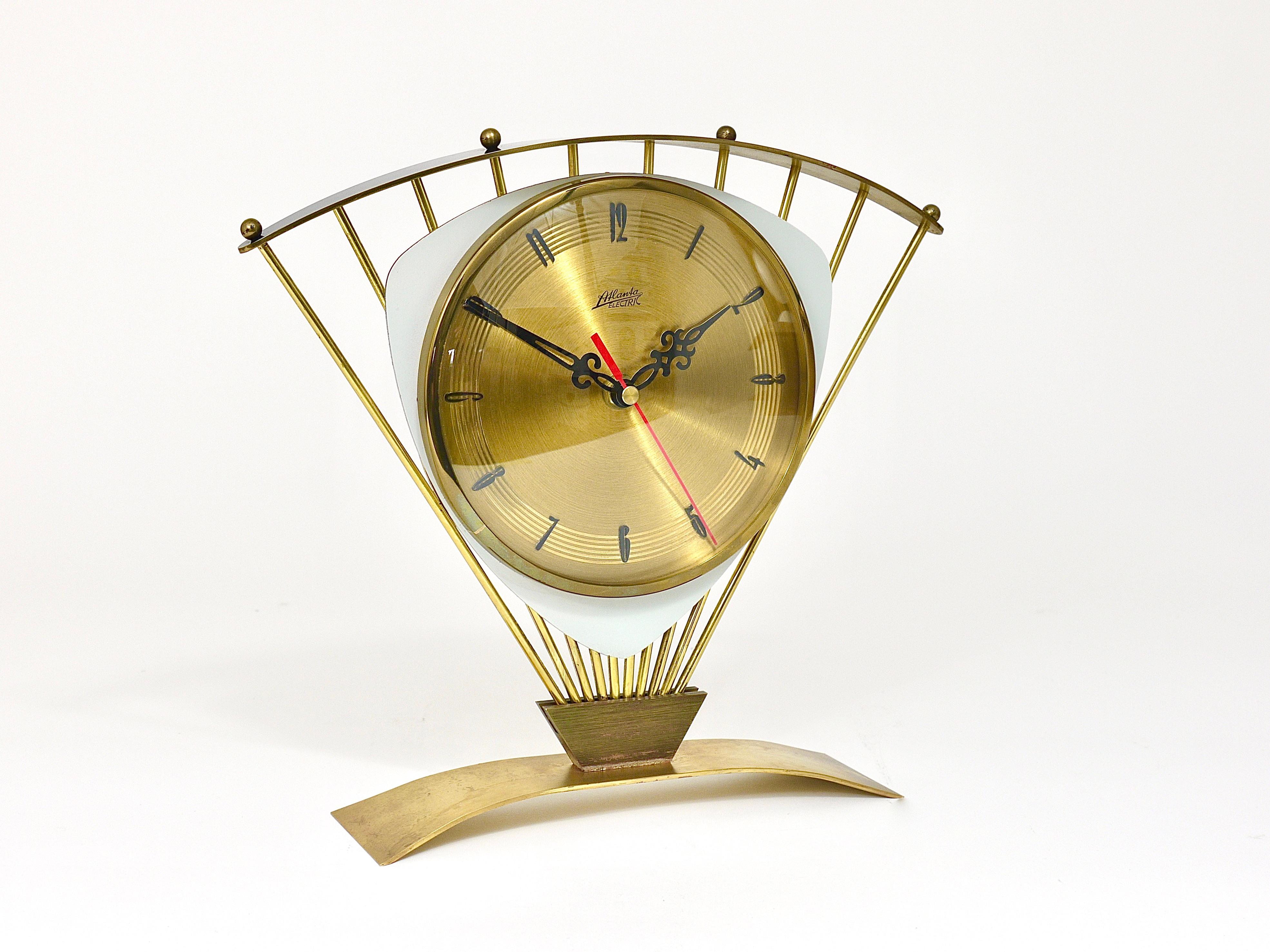An amazing midcentury triangular design starburst table or desk clock from the 1950s. Executed by Atlanta, Western Germany. Made of brass with a beautiful base, brass rays and a lovely black „roof“. Golden clocks face with charming 1950s numbers.