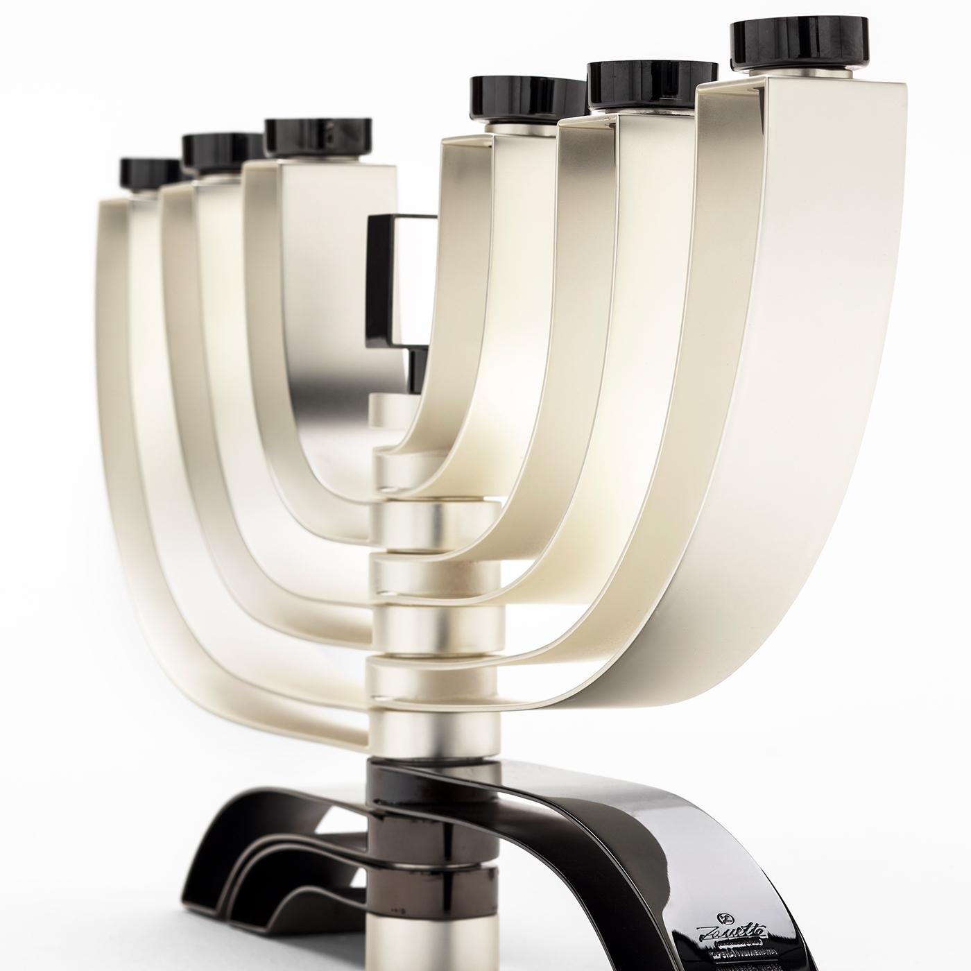 This superb table candelabra features a modern structure alternating titanium with satin silver. Boasting a sinuous and elaborate silhouette, the six shiny titanium candle holders are mounted on six pairs of silver arms, sustained on a titanium base