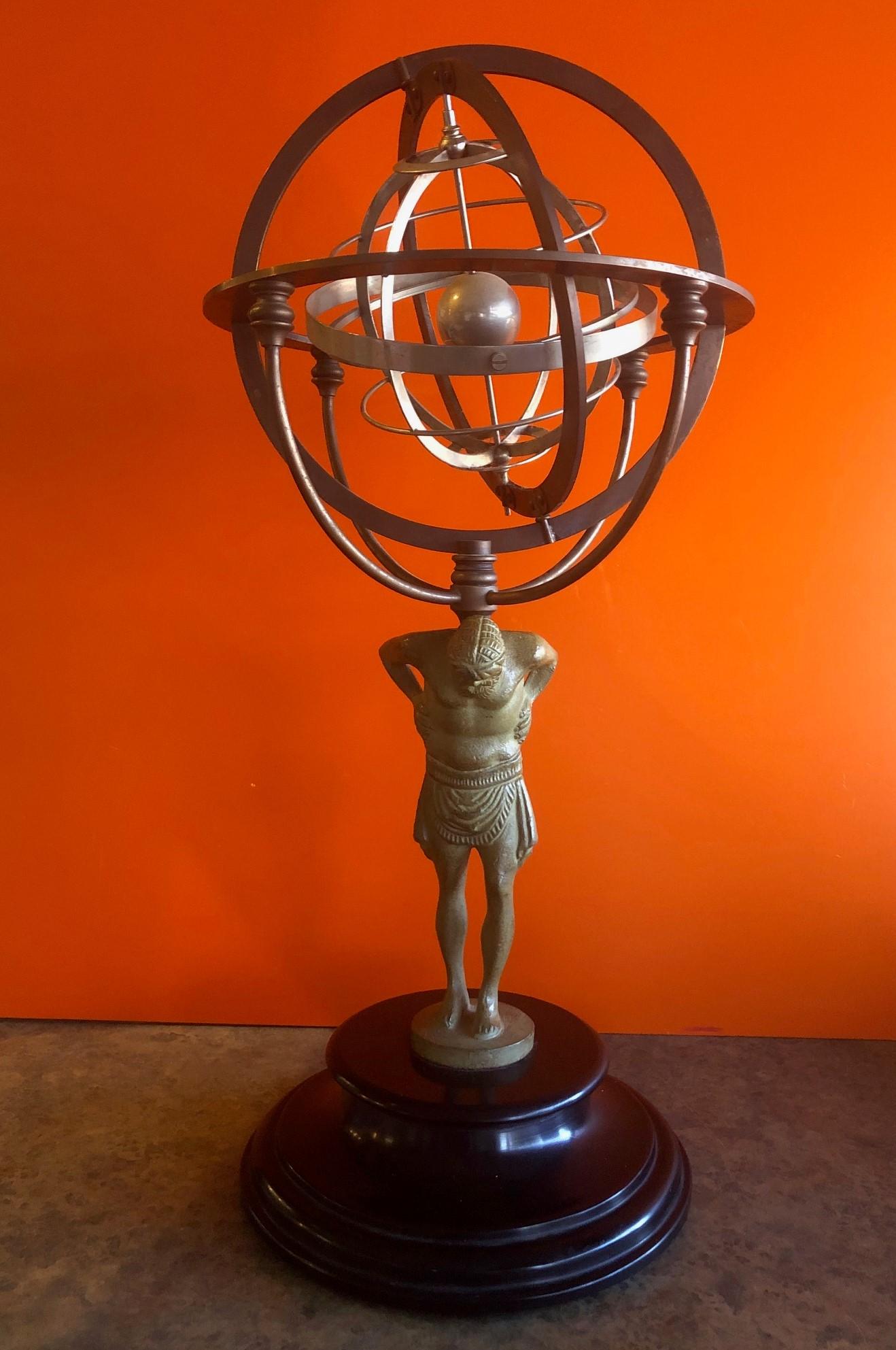 A very cool statue of Atlas with a mixed metals gyrating armillary sphere, circa 1970s. The piece is made of various metals including stainless steel, chrome and brass and sits on a round black marble base. The statue measures 22.5