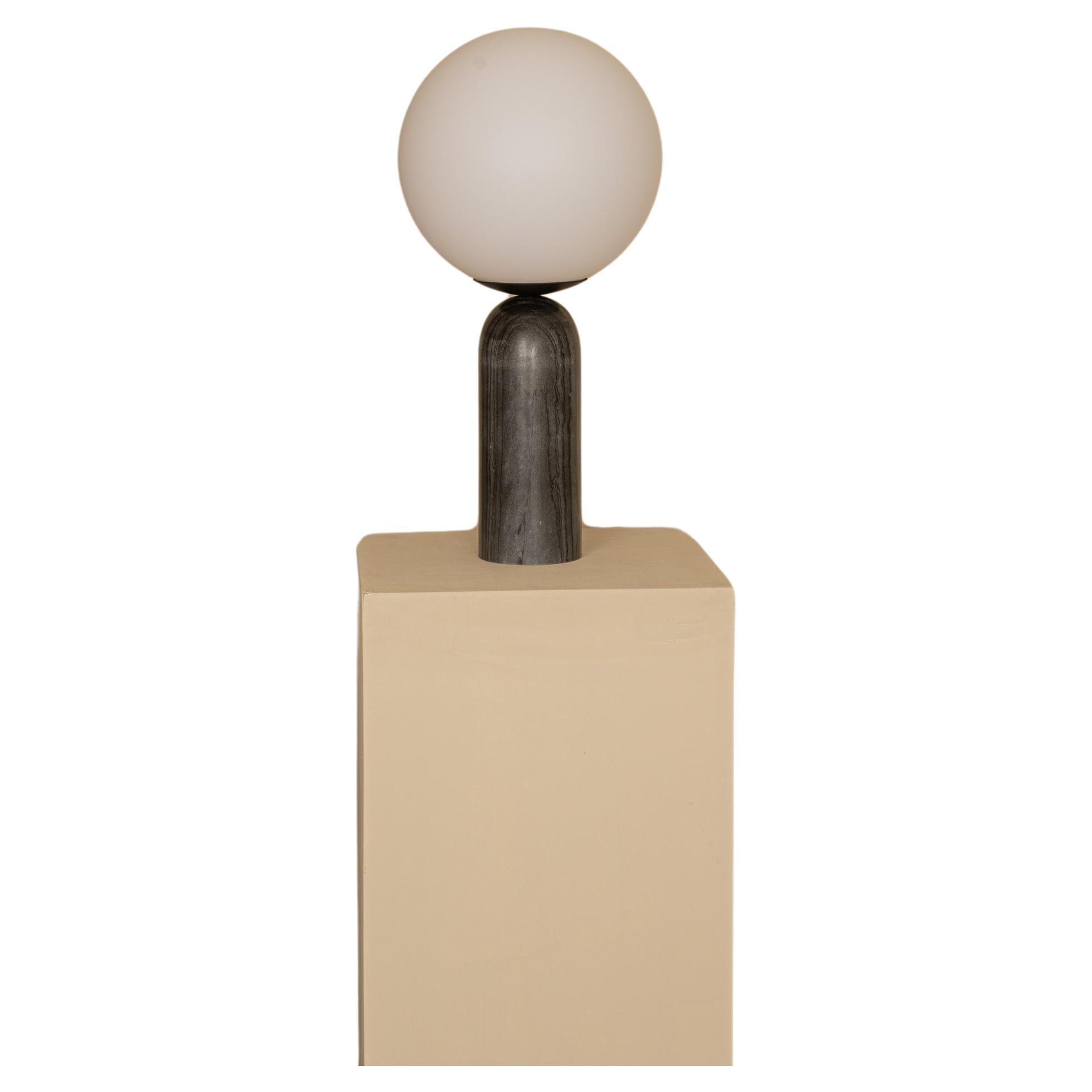 A modern representation of the greek mythology, the Atlas table lamp diffuses a beautiful light through its opal glass globe. The sphere sits on top of a minimal shaped base higlighted with a metal detail.
