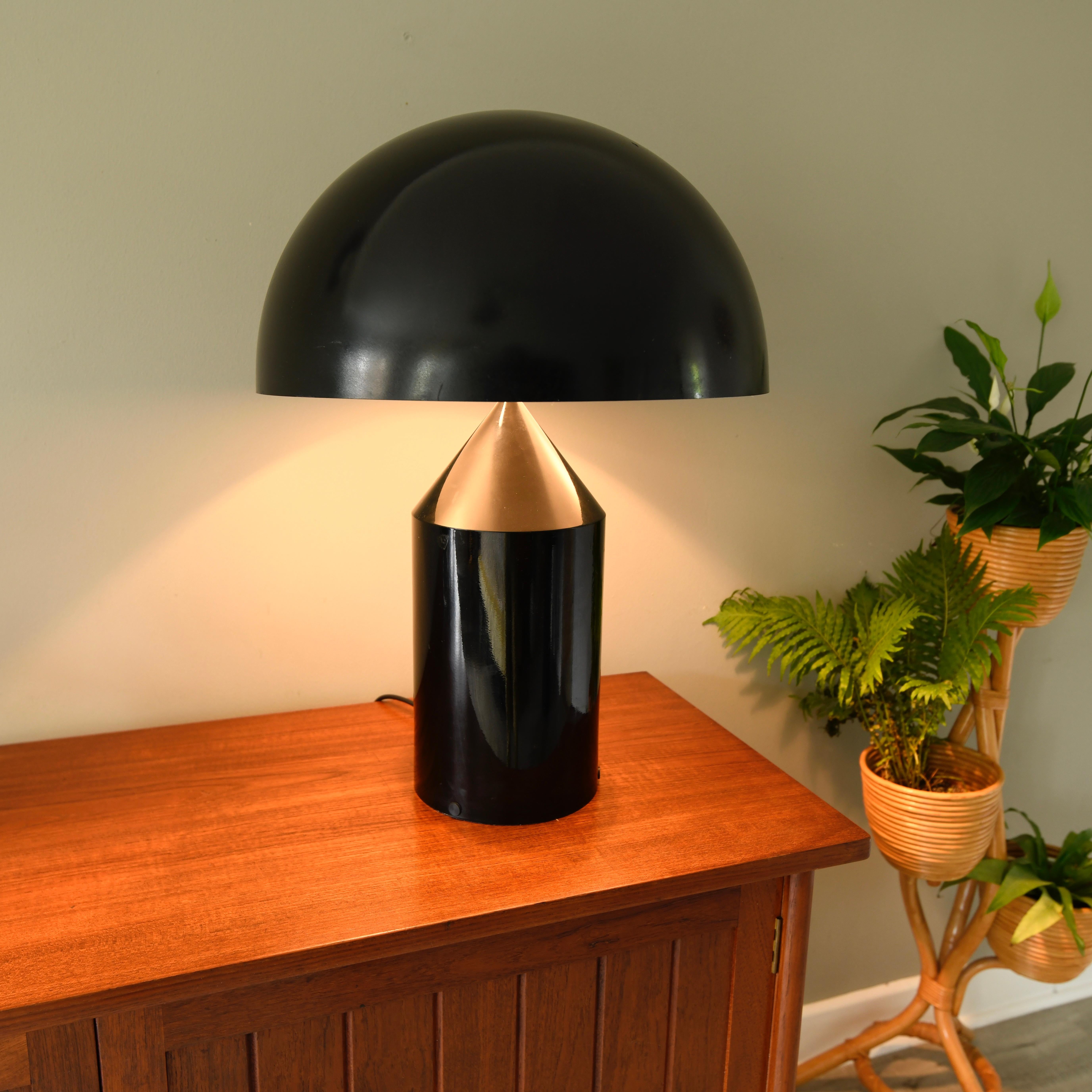 The Oluce Atollo 233 is a table lamp designed by Vico Magistretti from 1977. The lamp and the lampshade of Atollo 233 are made of lacquered aluminum and is black. The black shade is white inside. With a height of 70 cm it is one of the largest