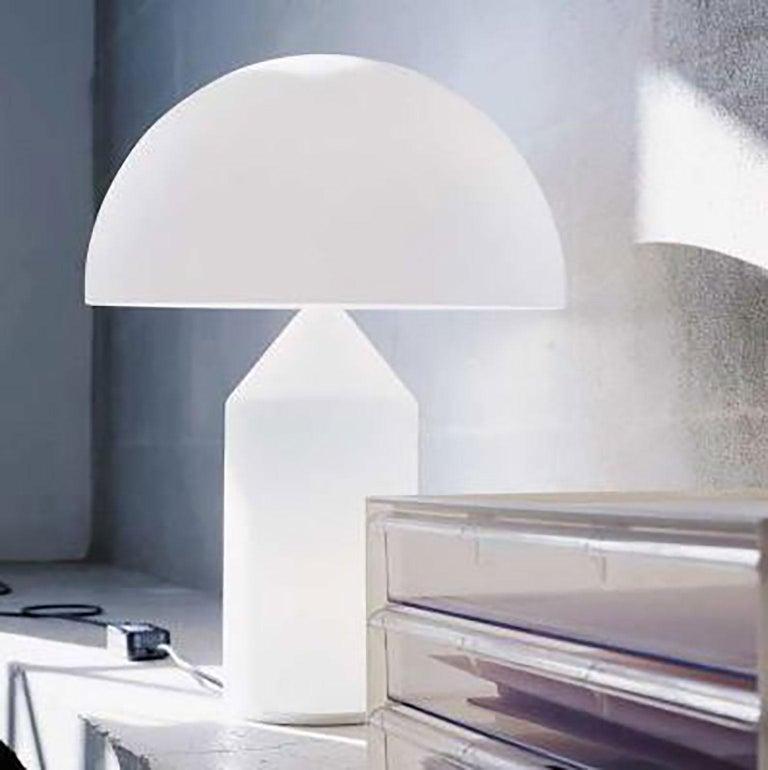 Lampe à poser Atollo par Vico Magistretti pour Oluce. La lampe Atollo est devenue une représentation iconique de la lampe de table. Le cylindre, le cône et l'hémisphère se combinent de manière si simple mais si forte que la forme suit la fonction.