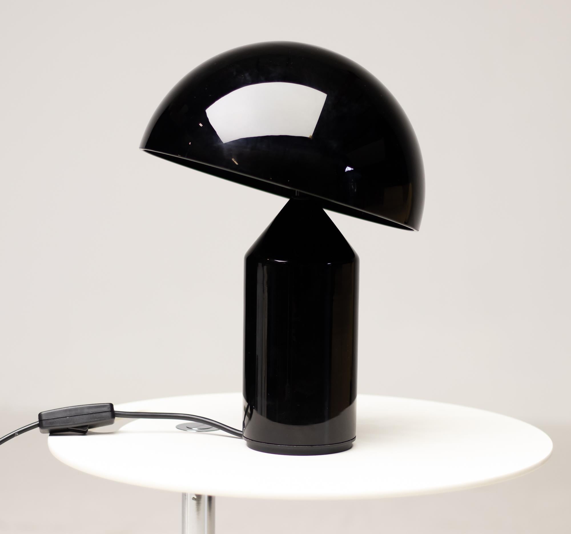 Iconic Atollo model 236 table lamp designed in 1977 by Vico Magistretti for oluce. Over the years, Atollo has become the archetype of the table lamp, winning the Compasso d’Oro in 1979. Provides direct light as a table or bedside lamp. 
Black glass