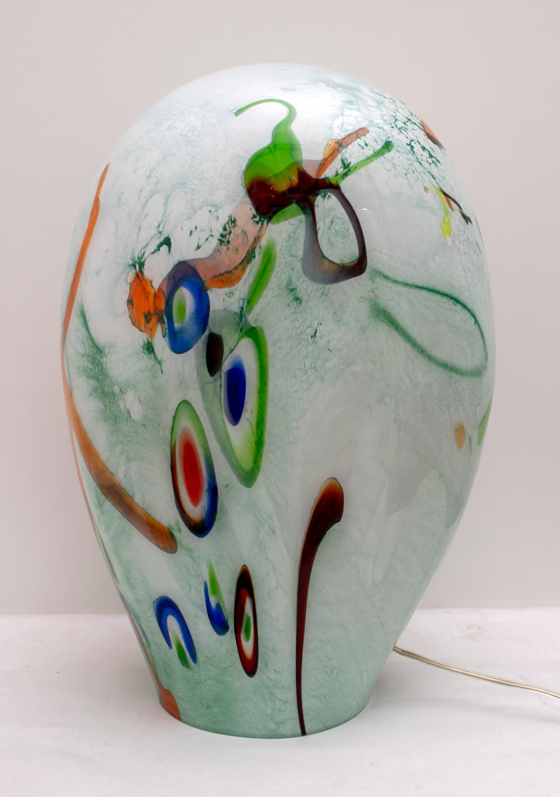 This table lamp was produced in Murano glass with three layers of different glass: transparent, white and colored Murrine glass. Produced by the company Muranocom in 2000, a company from Murano that no longer exists.

