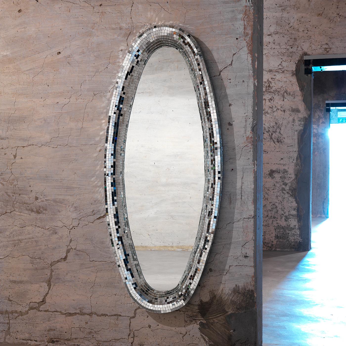 Taking center stage on a bare wall in an entryway or living room, this superb mirror will create an enchanting effect in any interior with its elongated and glimmering silhouette. The oval frame is made of a mirrored glass mosaic with a silver