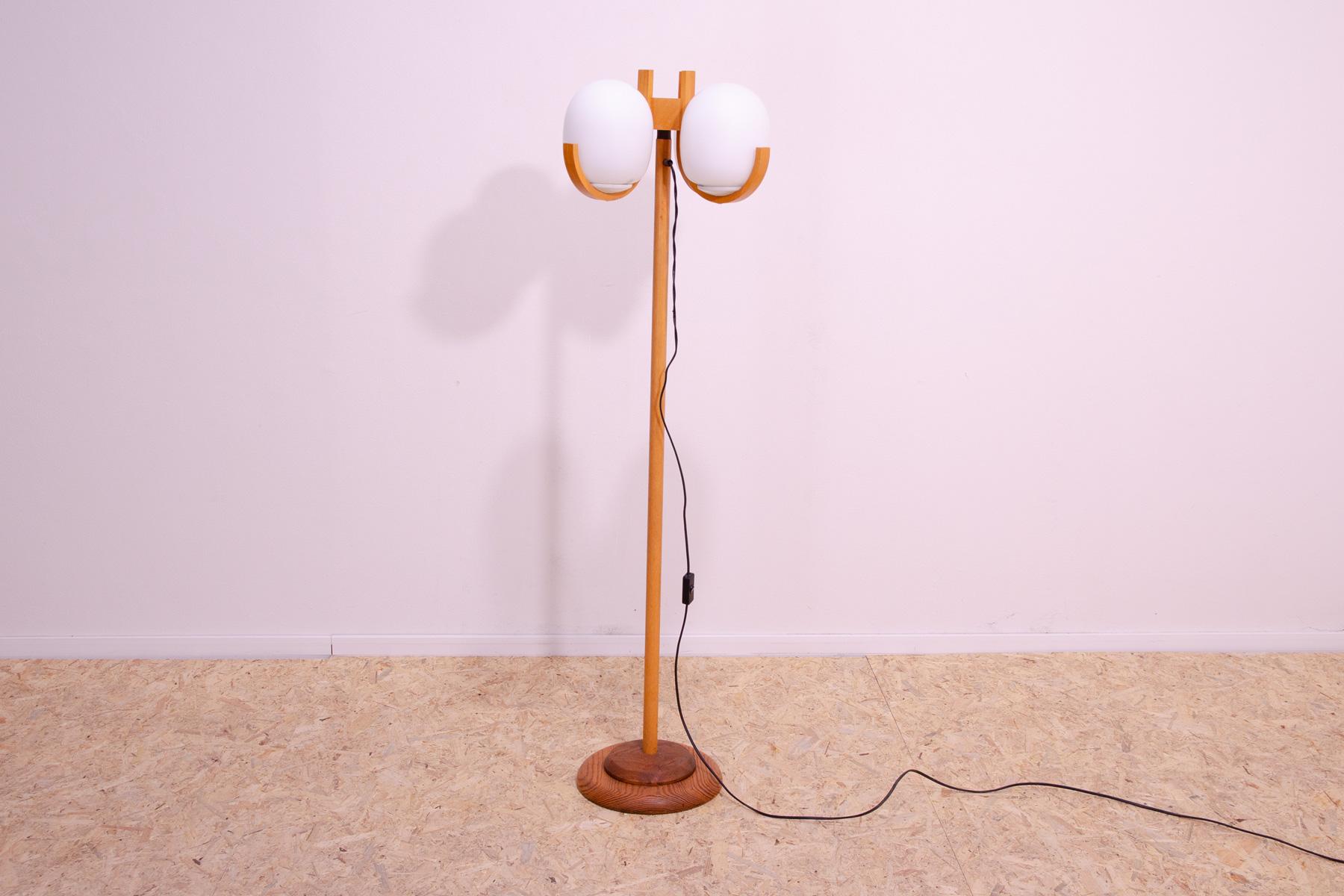 A relatively rarely seen floor lamp made in the 70s of the last century in the former Czechoslovakia. It was most likely part of a hotel room equipment.

The lamp is made of white opaque glass with a matte surface and an all-wood frame made of beech