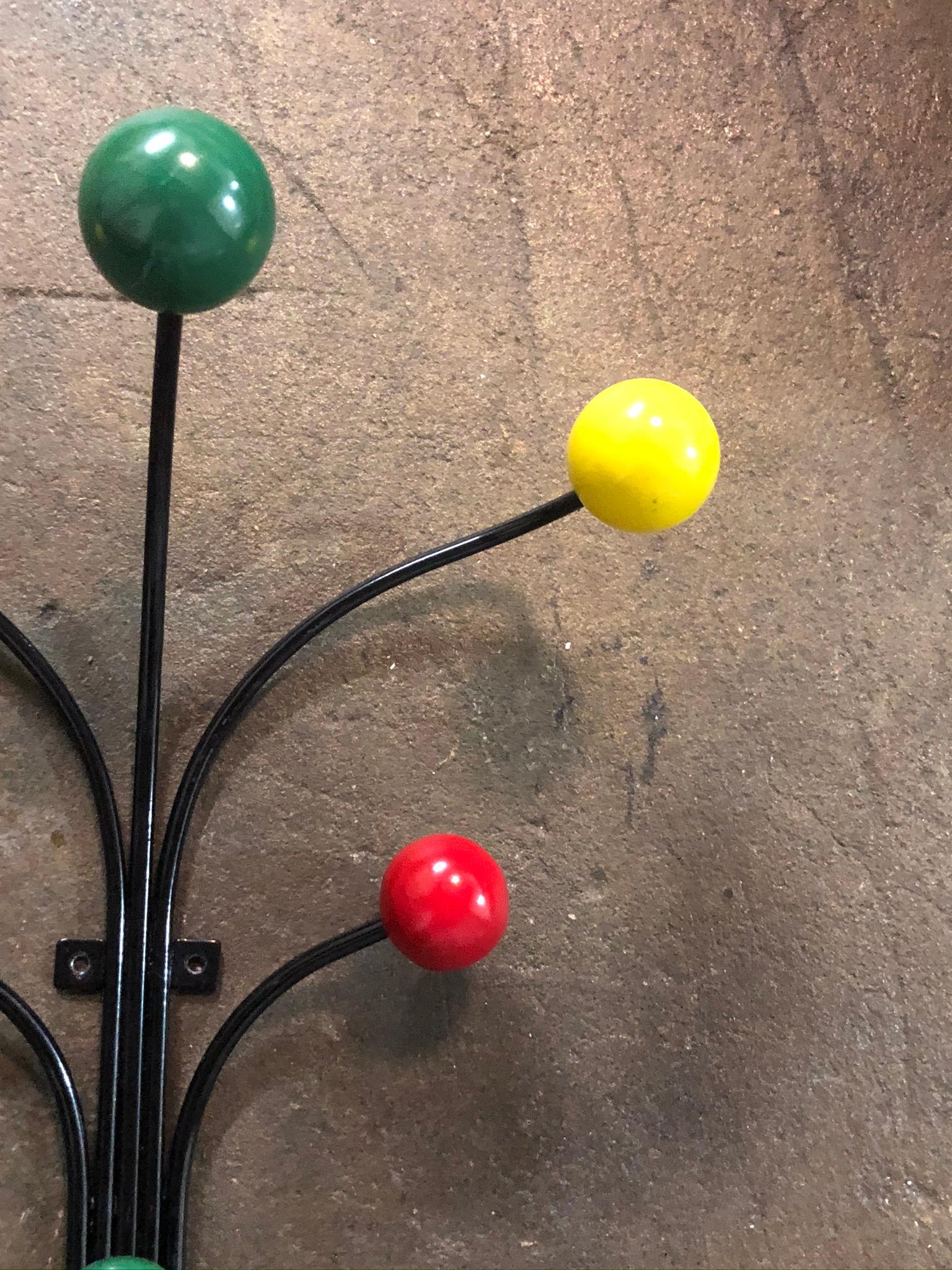 Beautiful decorative coat rack wall hanger. Black metal frame with colored accent wooden ball ends. Can support several coats and umbrellas. Looks just as good without anything on it!