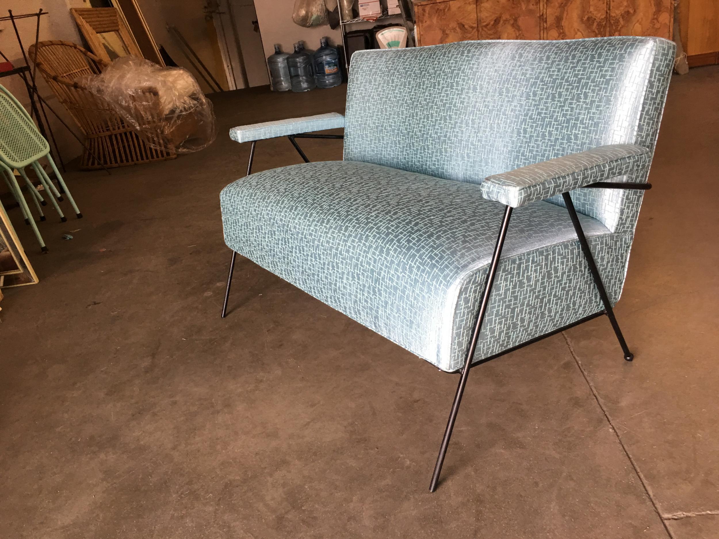 All original Atomic Age loveseat sofa featuring blue/green lined fabric seat with wrought iron legs with built-in armrest.