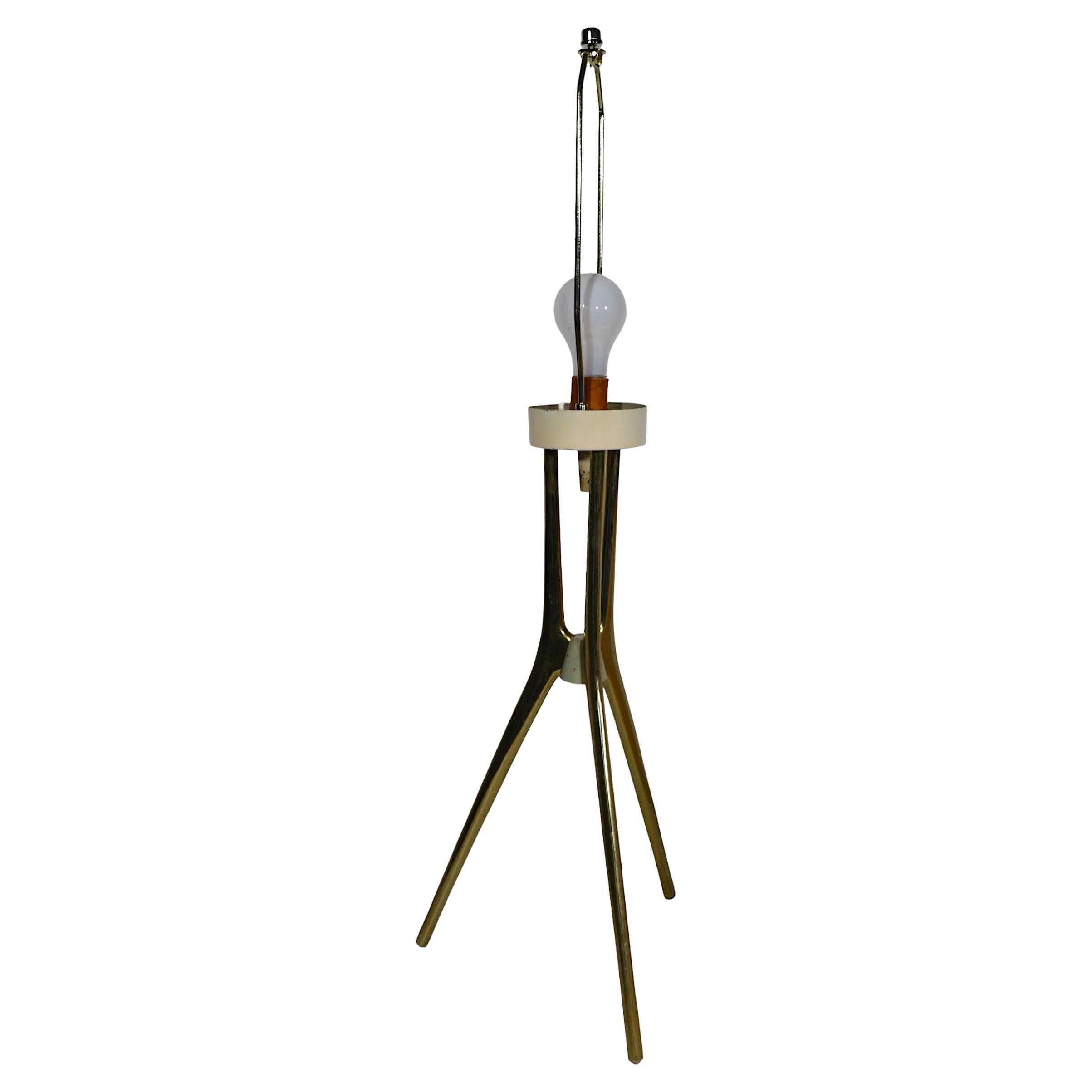 Architectural Mid Century, Atomic, Space Age jack form table lamp, by Lightolier, design attributed to Gerald Thurston. The lamp features a tripod base of elegant sculptural brass legs, the harp and finial which hold the shade  are later