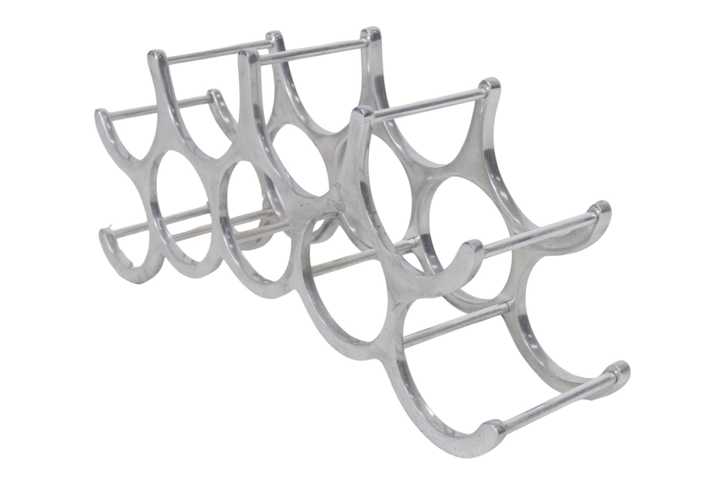 An atomic style wine rack made of polished aluminum. Four over five circles and semi circles hold up to nine bottles of wine in a decorative arch.
 