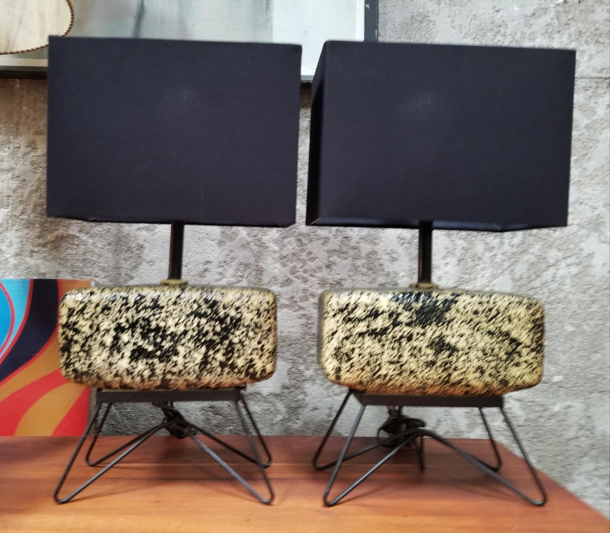 A pair of ceramic and steel atomic Space Age table lamps by Aladdin. Mottled yellow and black ceramic body supported by a painted black steel hair-pin style base. New shades. Reaching the on/off switch is a bit cumbersome as you mush reach up under