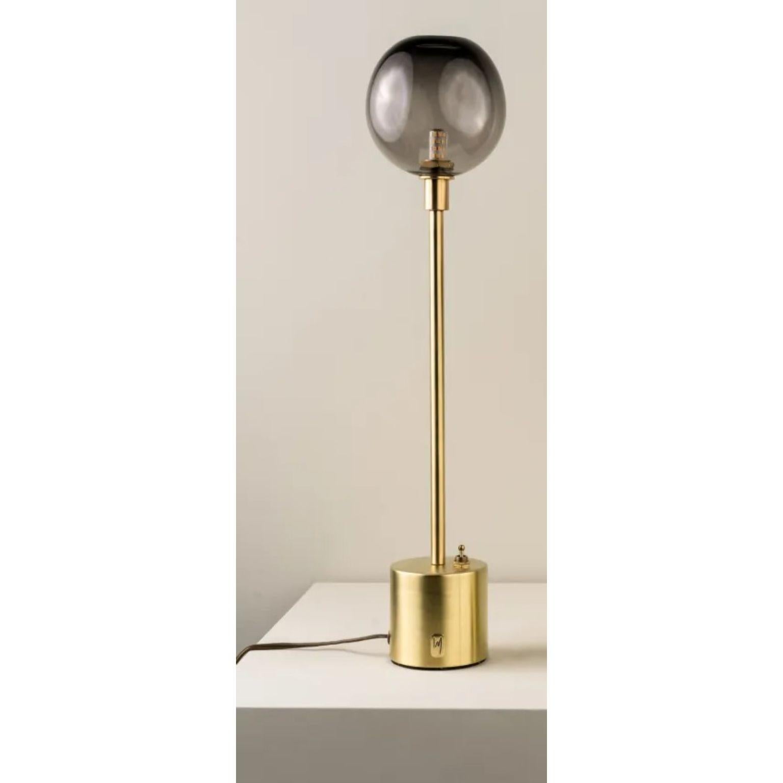 Átomo Smoke Blown Glass and Brass Table Lamp by Isabel Moncada
Dimensions: Ø 13 x H 33 cm.
Materials: Brass, steel and blown glass.

Átomo is perfect to give a touch of silent light, almost like a sparkle. The simplicity of its globe is enough, a