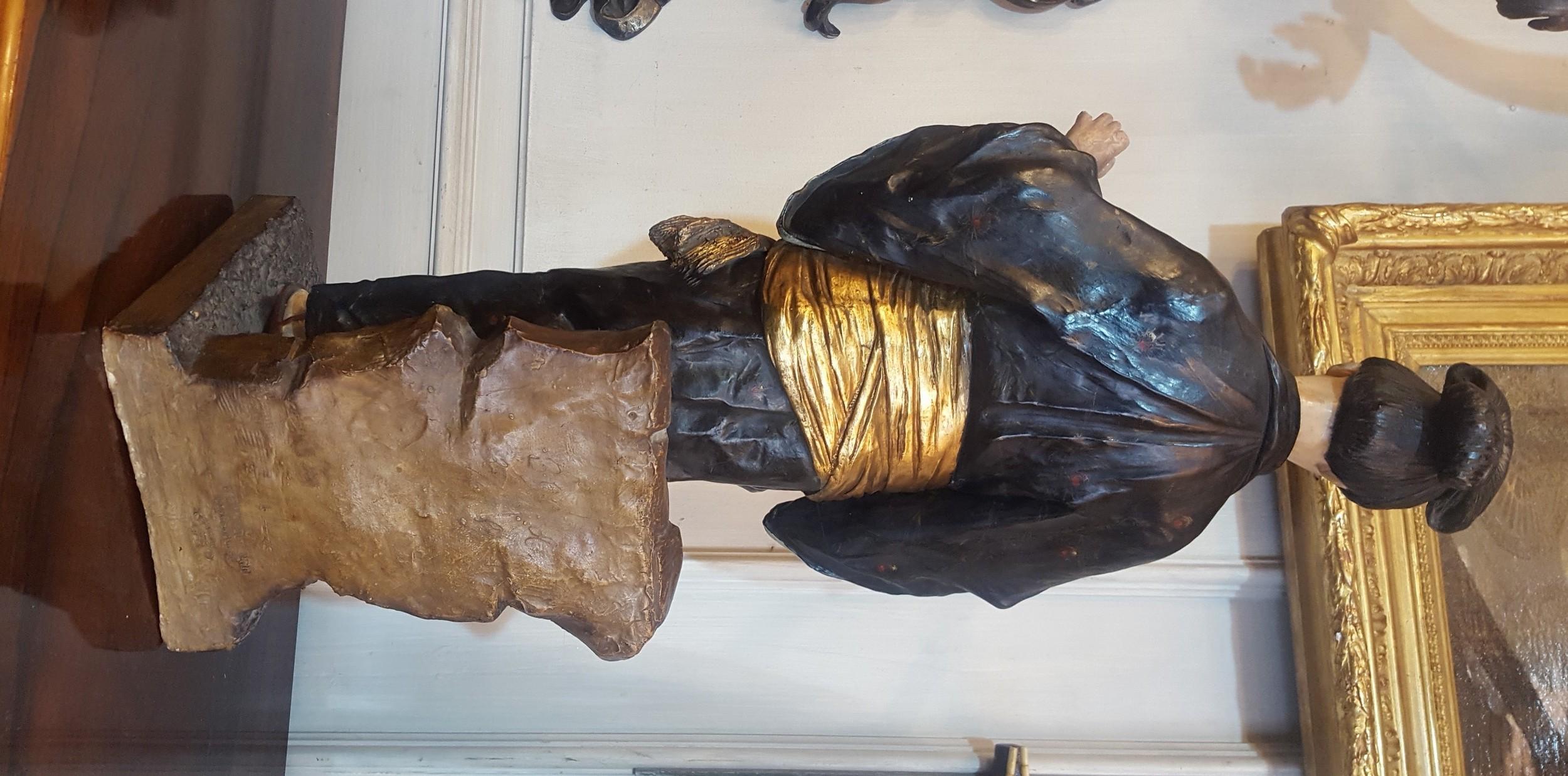 Belle sculpture en terre cuite peinte représentant une femme japonaise en tenue traditionnelle : elle porte un kimono décoré de fleurs rouges et jaunes sur fond noir, un grand obi doré et des sandales en bois. Ses cheveux sont attachés sur sa tête