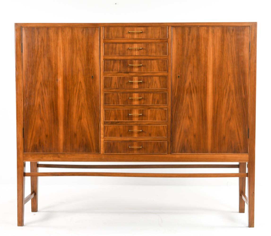 A very handsome Danish mid-century tall sideboard in mahogany attributed to Jakob Kjær. Featuring two side cabinets with maple interior consisting of adjustable shelving and central drawers with elegant mid-century brass pulls, fitted with green