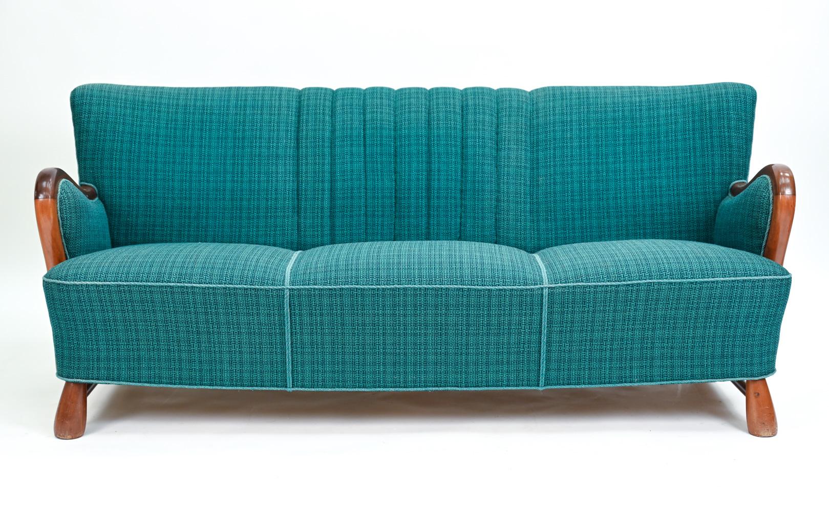 A handsome and comfortable Danish Art Deco period sofa attributed to Otto Faerge, of quality design and construction. Featuring a mahogany frame with flared arms, a slight wingback design, and teal wool tweed upholstery, channel-stitched at the