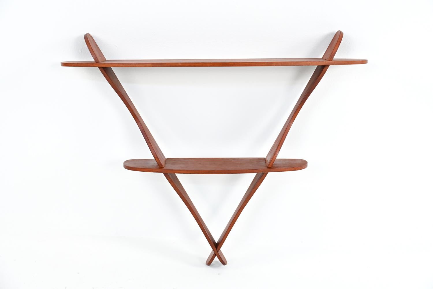 A Danish mid-century organic triangular-form wall-mount two-tier shelf in teak wood, attributed to eccentric designer Peder Moos, 1950's. A stylish and functional example of Scandinavian modern design. No apparent markings.